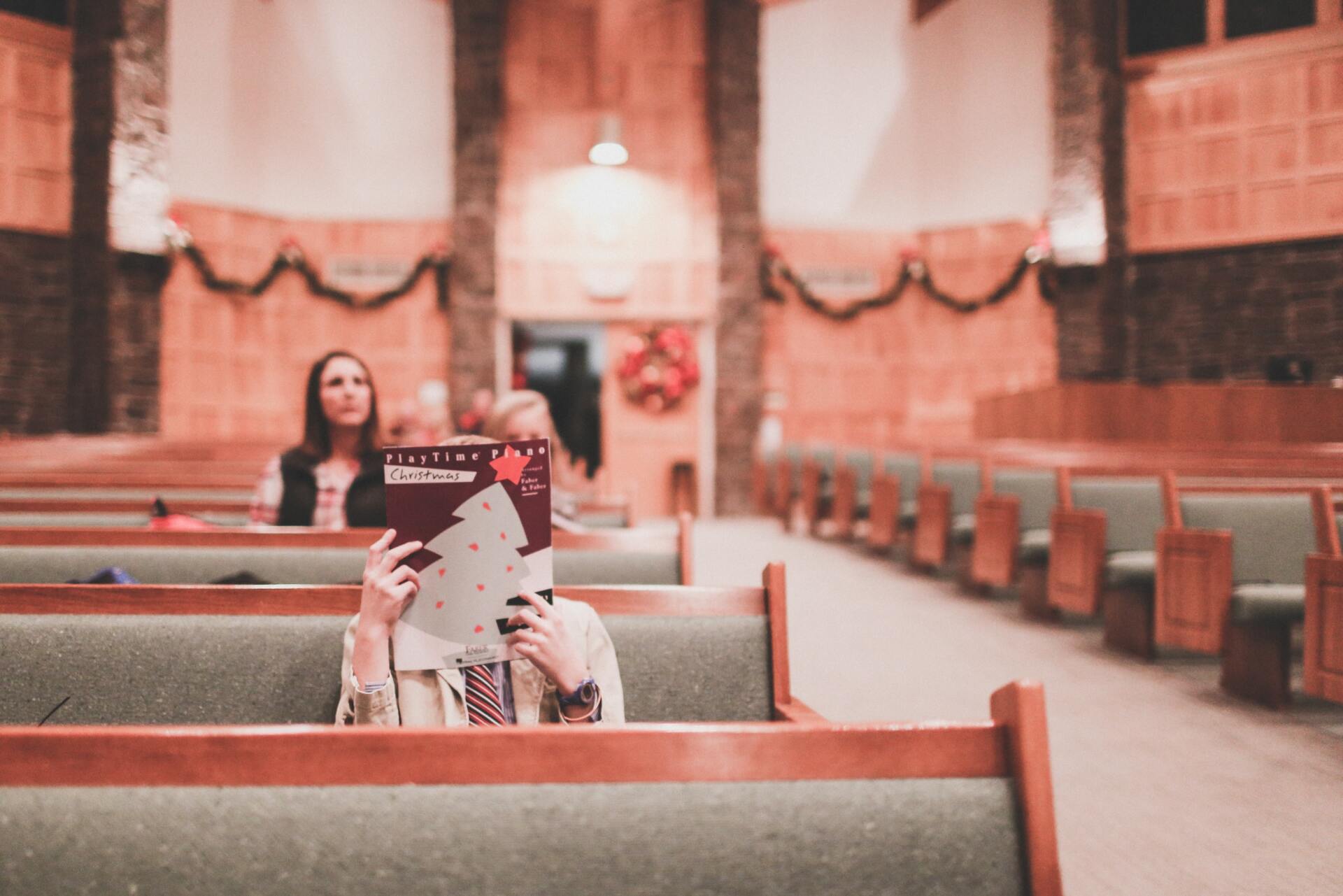 A woman is sitting in a church reading a book.