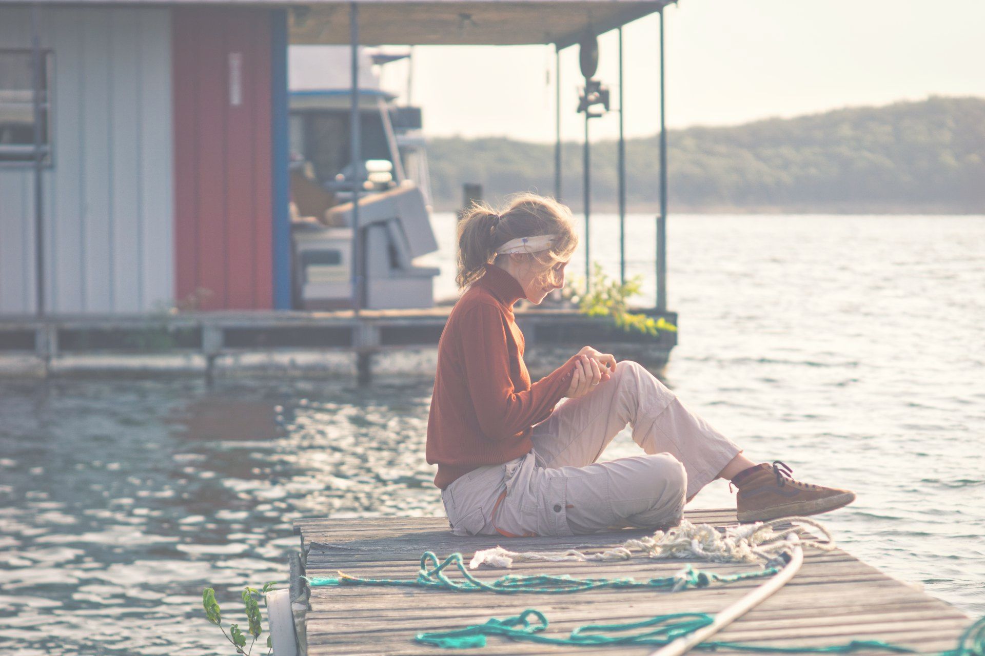 A woman is sitting on a dock looking at her phone.