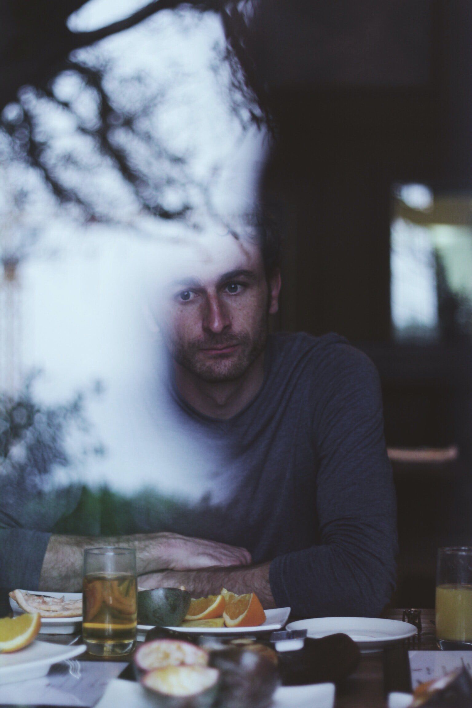 A man sits at a table with plates of food and a glass of beer