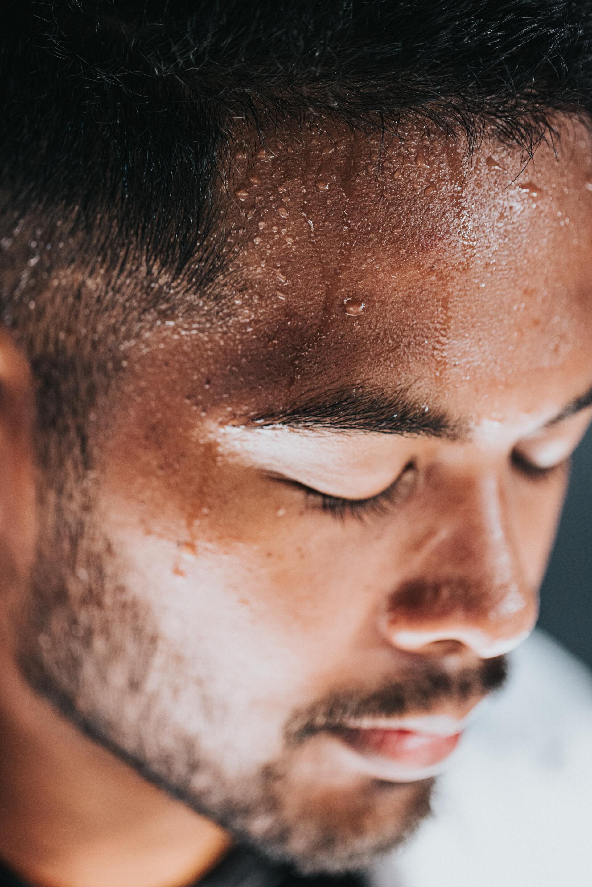 A close up of a man 's face with sweat on it.