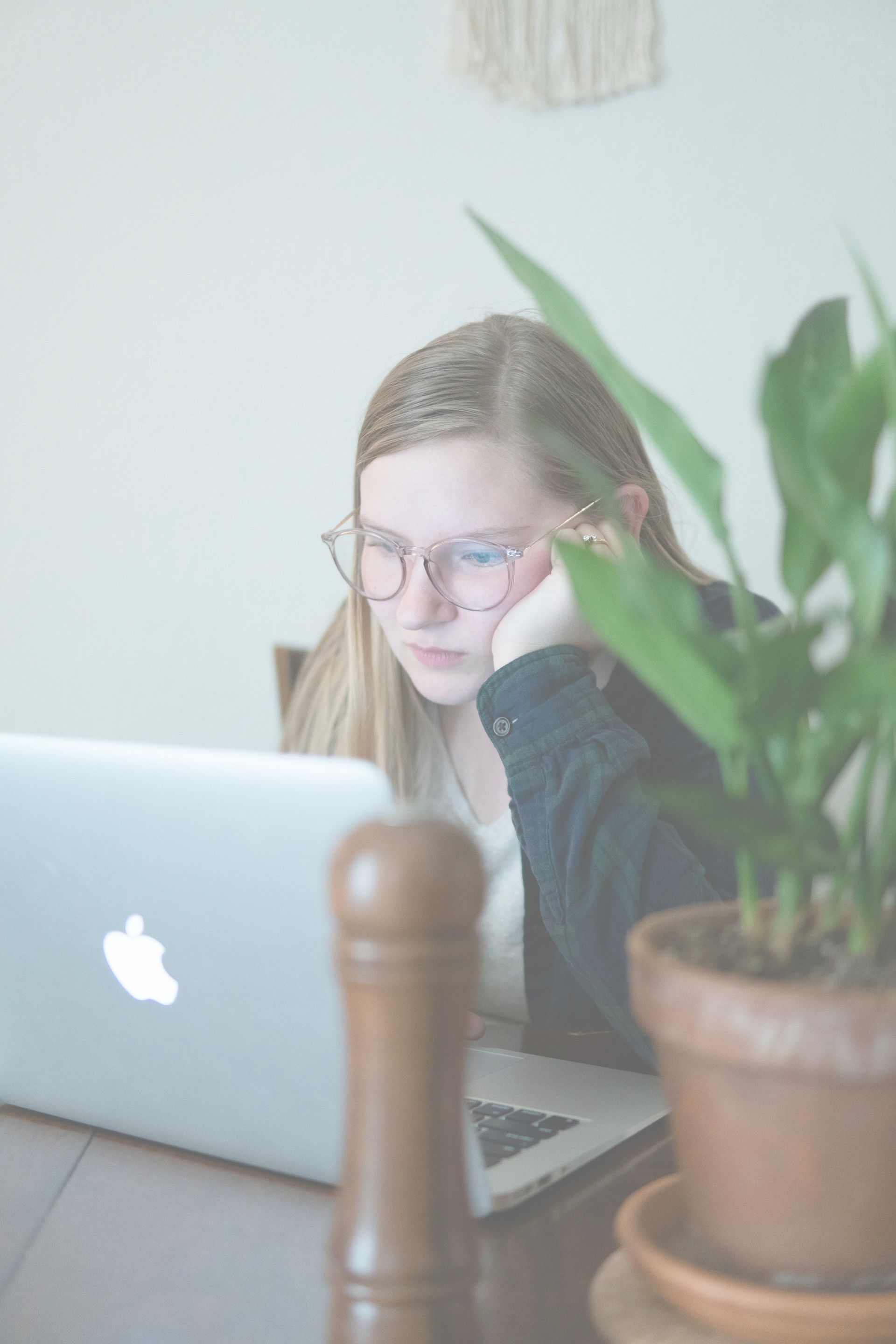A young girl is sitting at a table using a laptop computer.