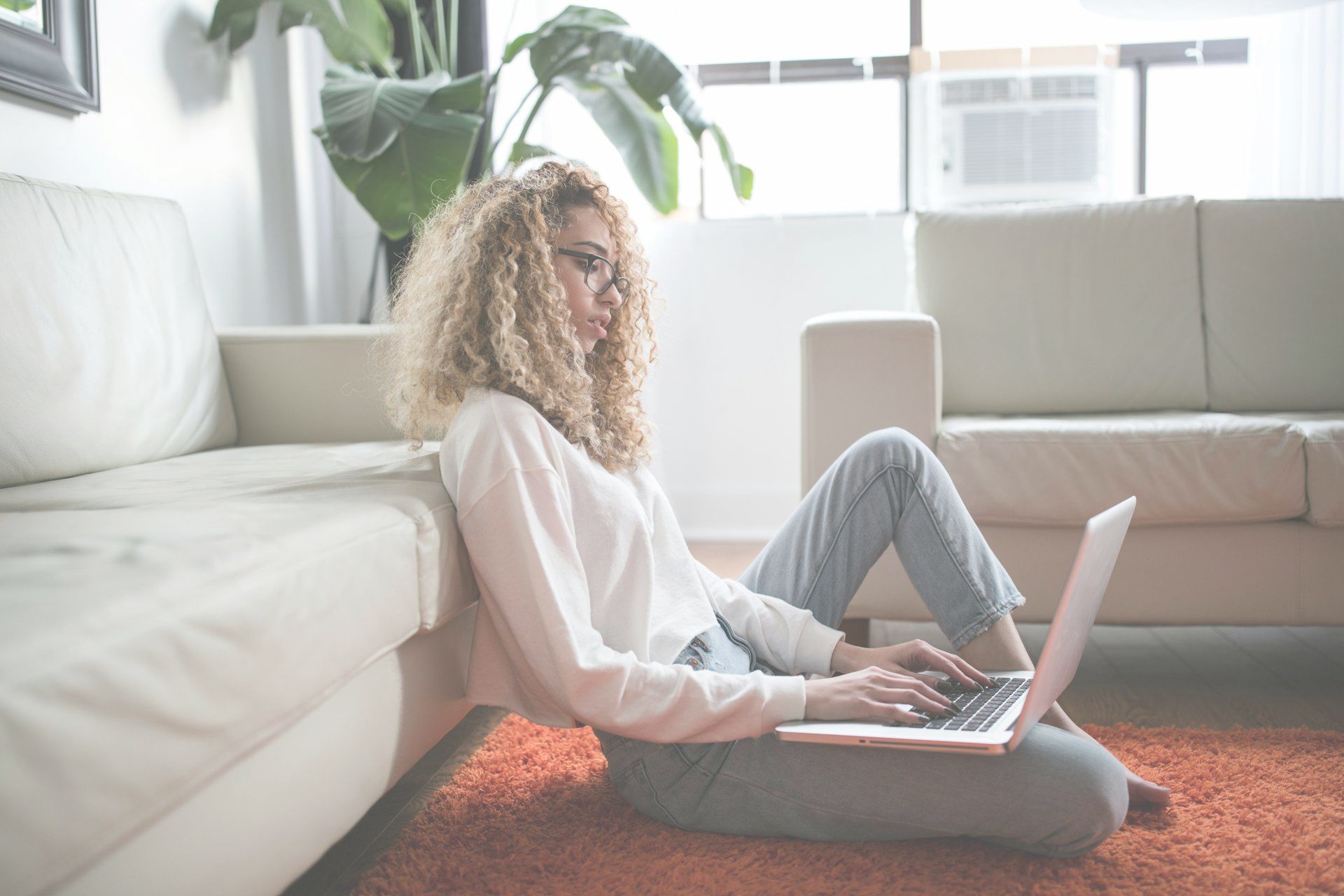 A woman is sitting on the floor using a laptop computer.
