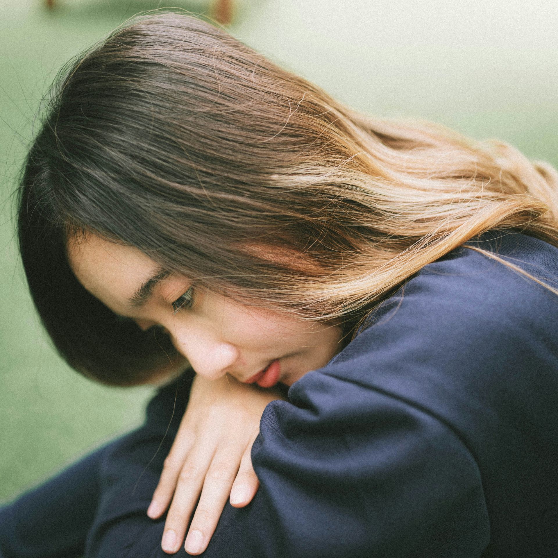 Asian woman looks down, experiencing anxiety after a traumatic event. 