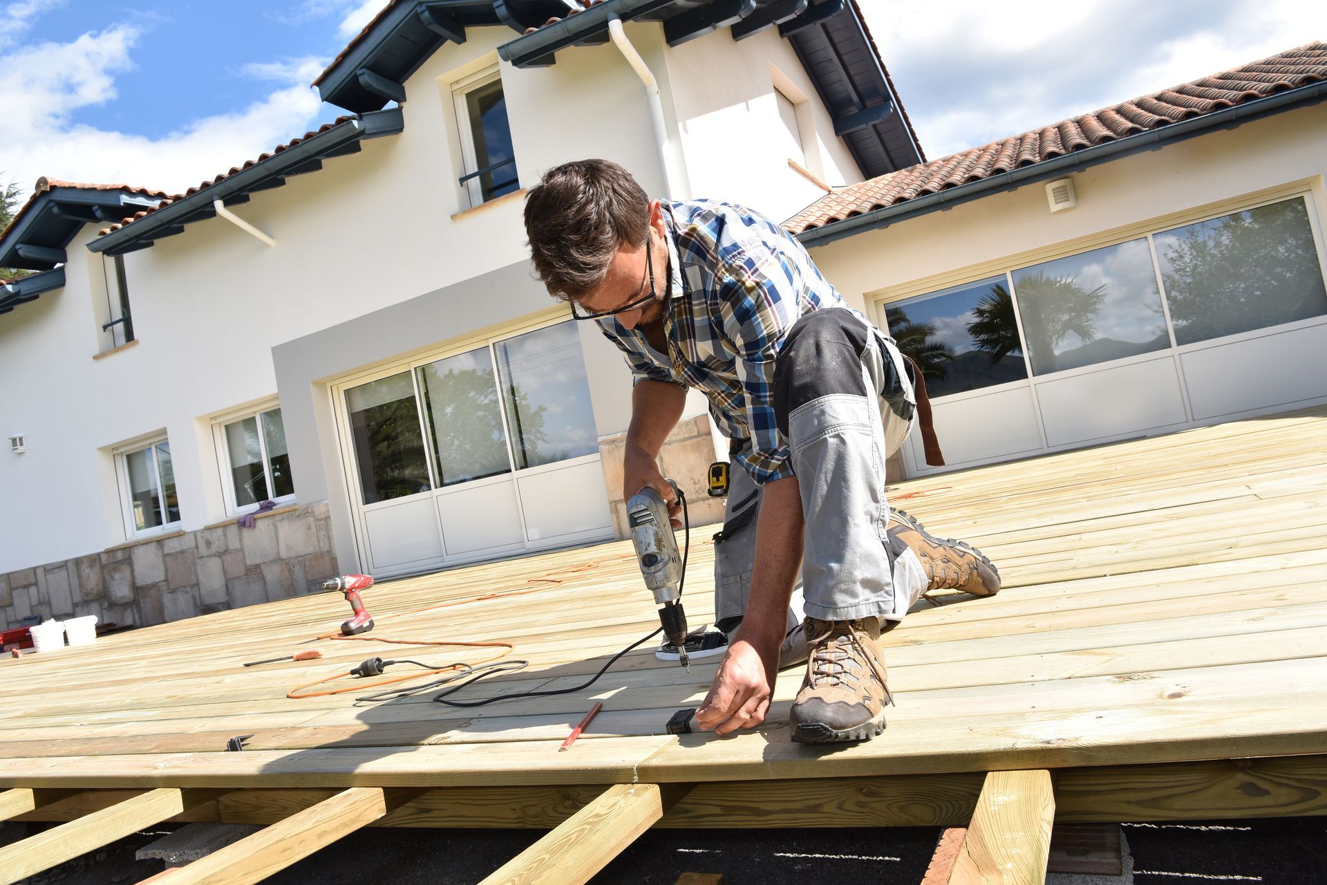 Worker installing wooden decking on a house patio under construction