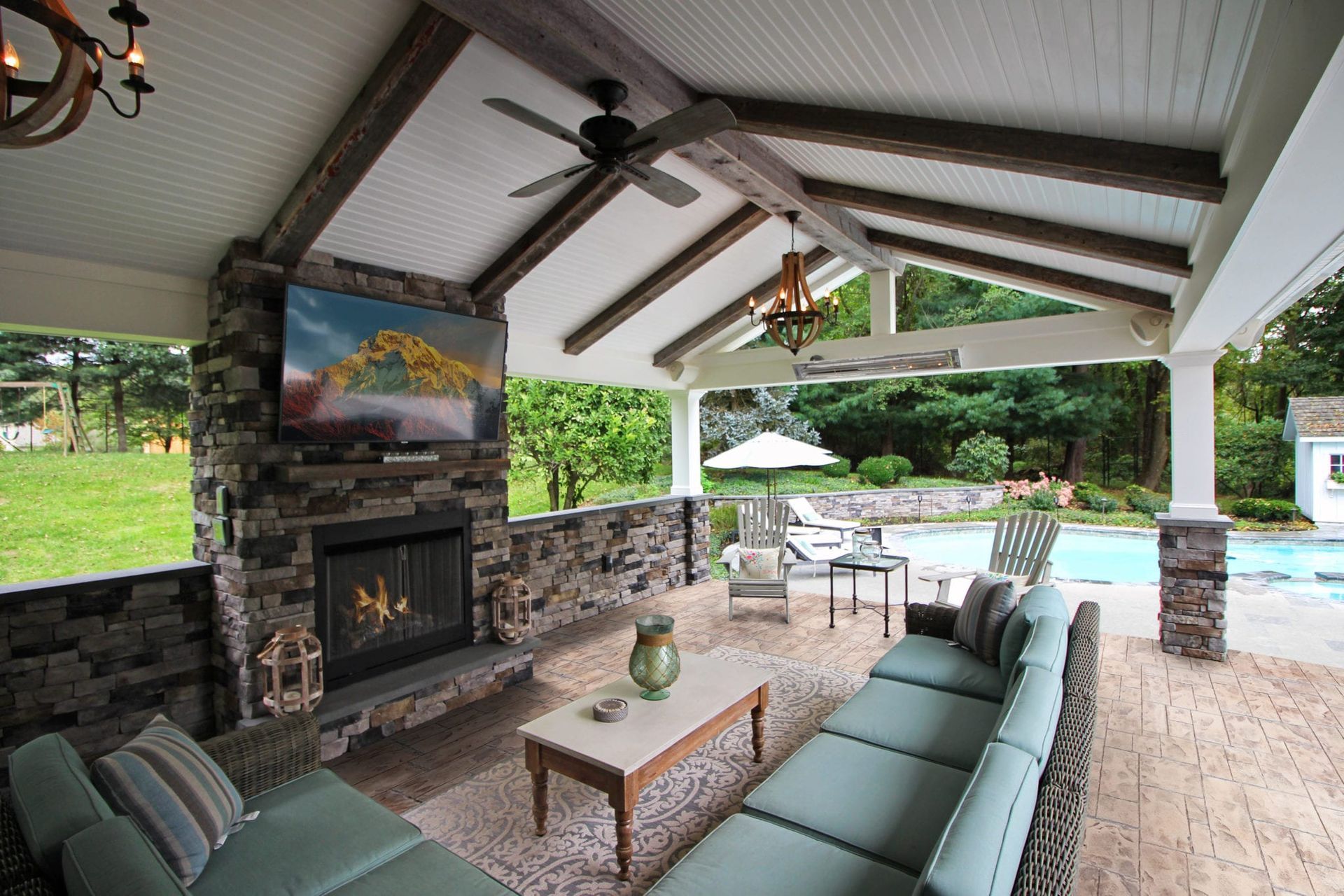 Covered patio lounge with fireplace, sectional seating, and pool view
