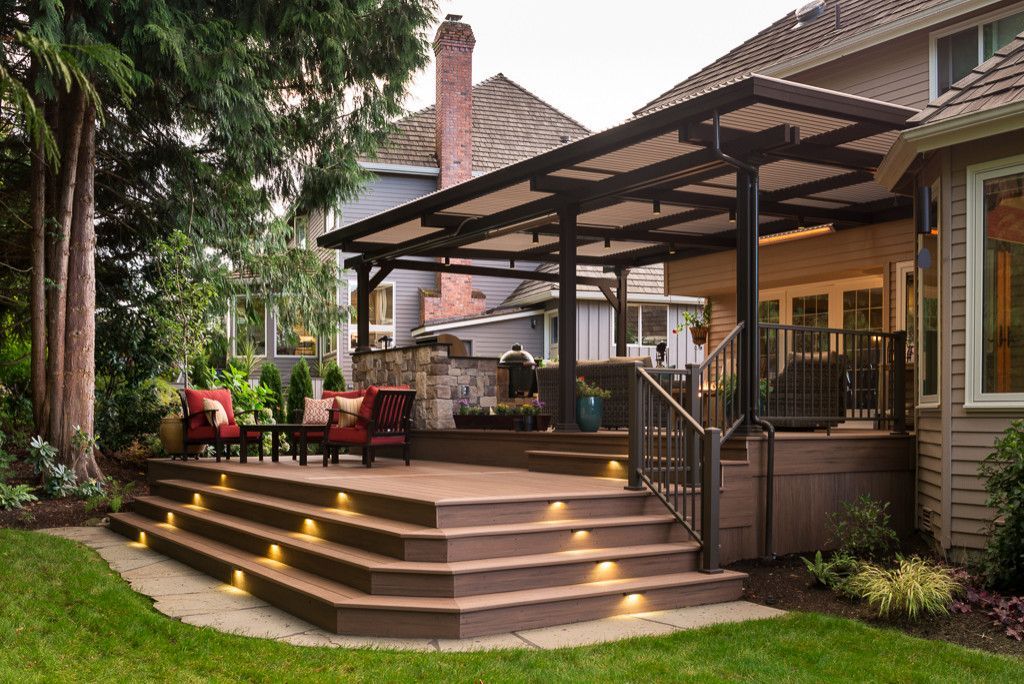 Backyard deck with pergola, lit steps, and red patio seating beside a house