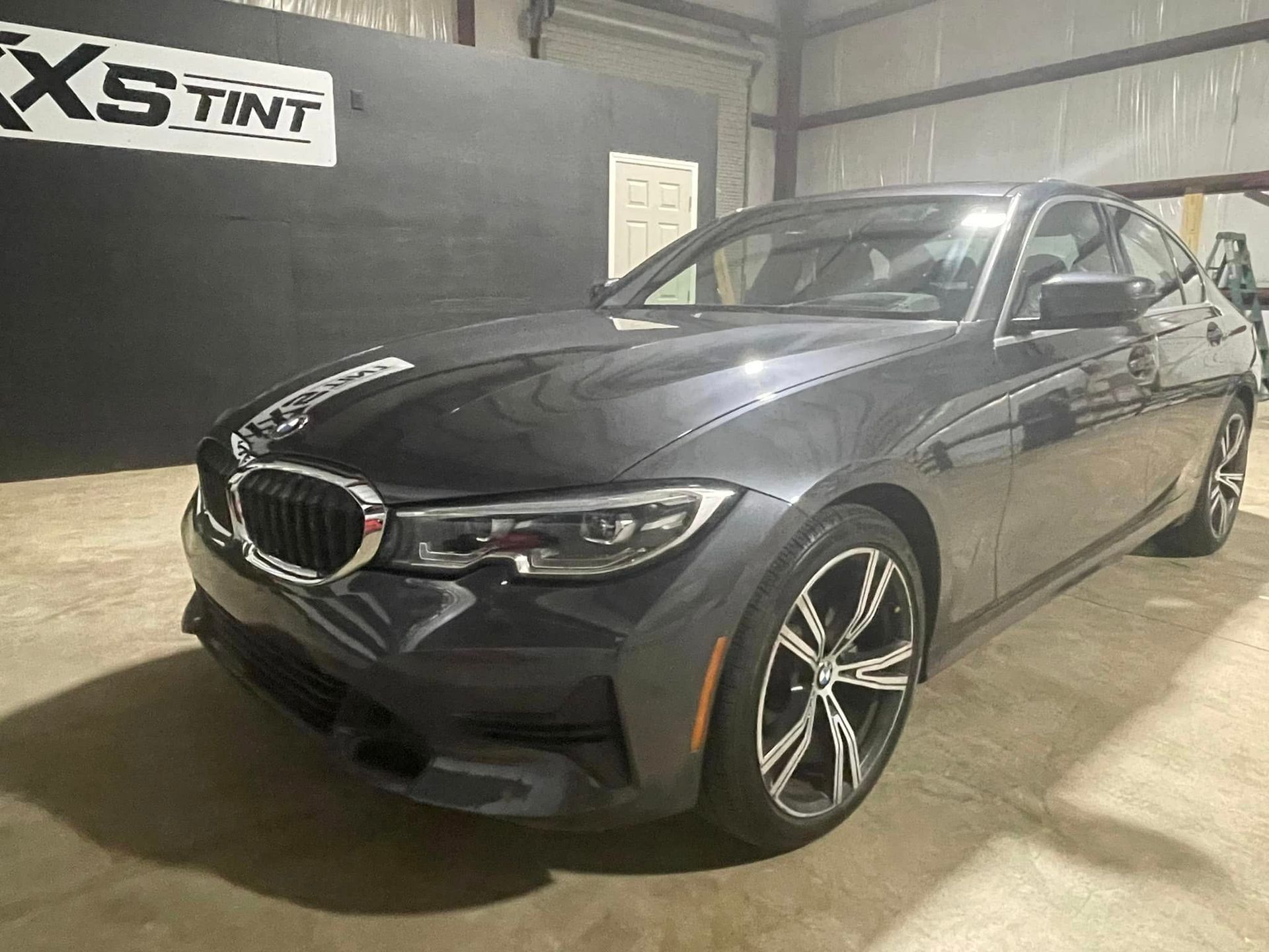 A black bmw 3 series is parked in a garage.