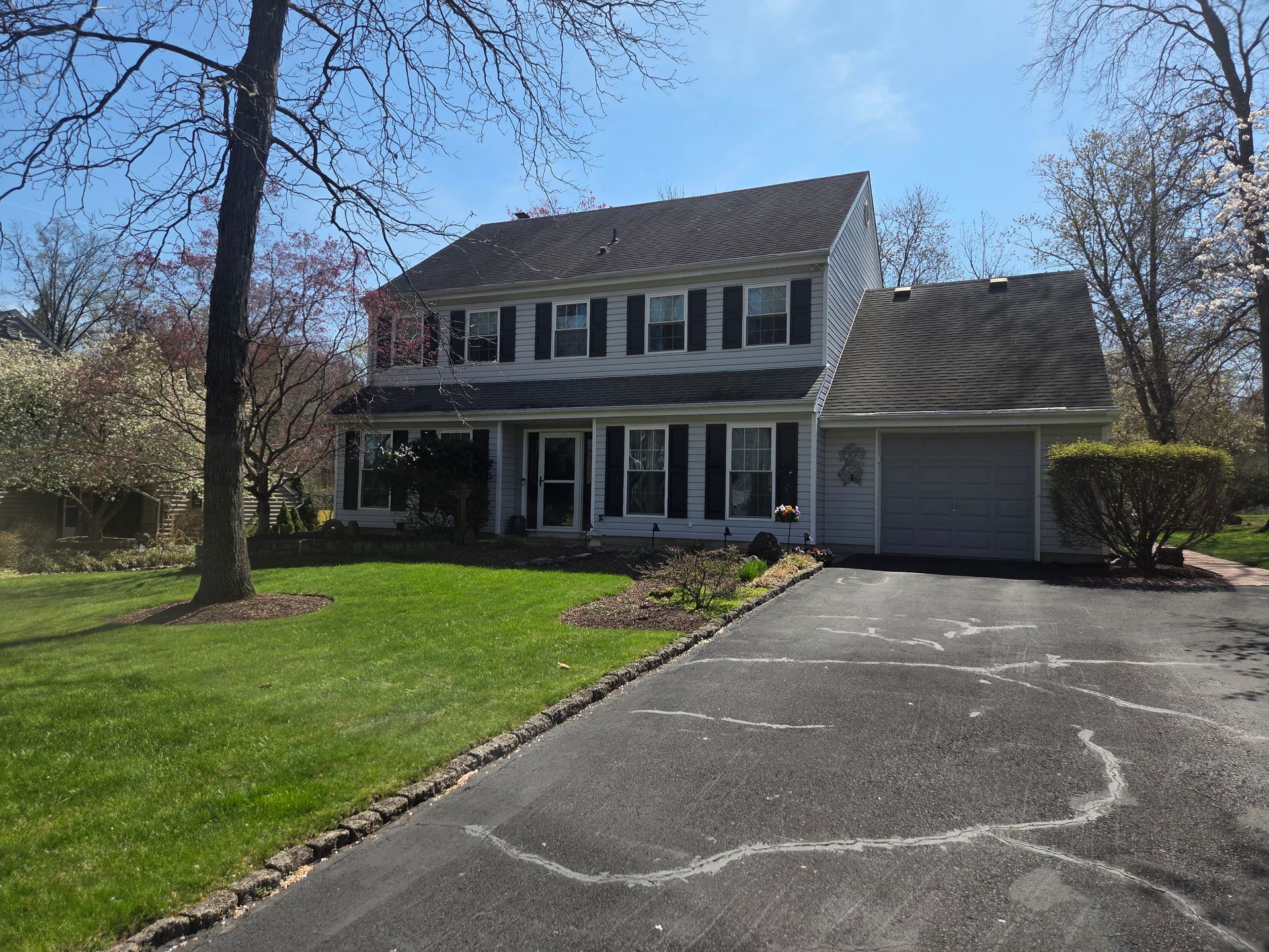 Two-story suburban house with a garage, driveway, and front lawn on a sunny day