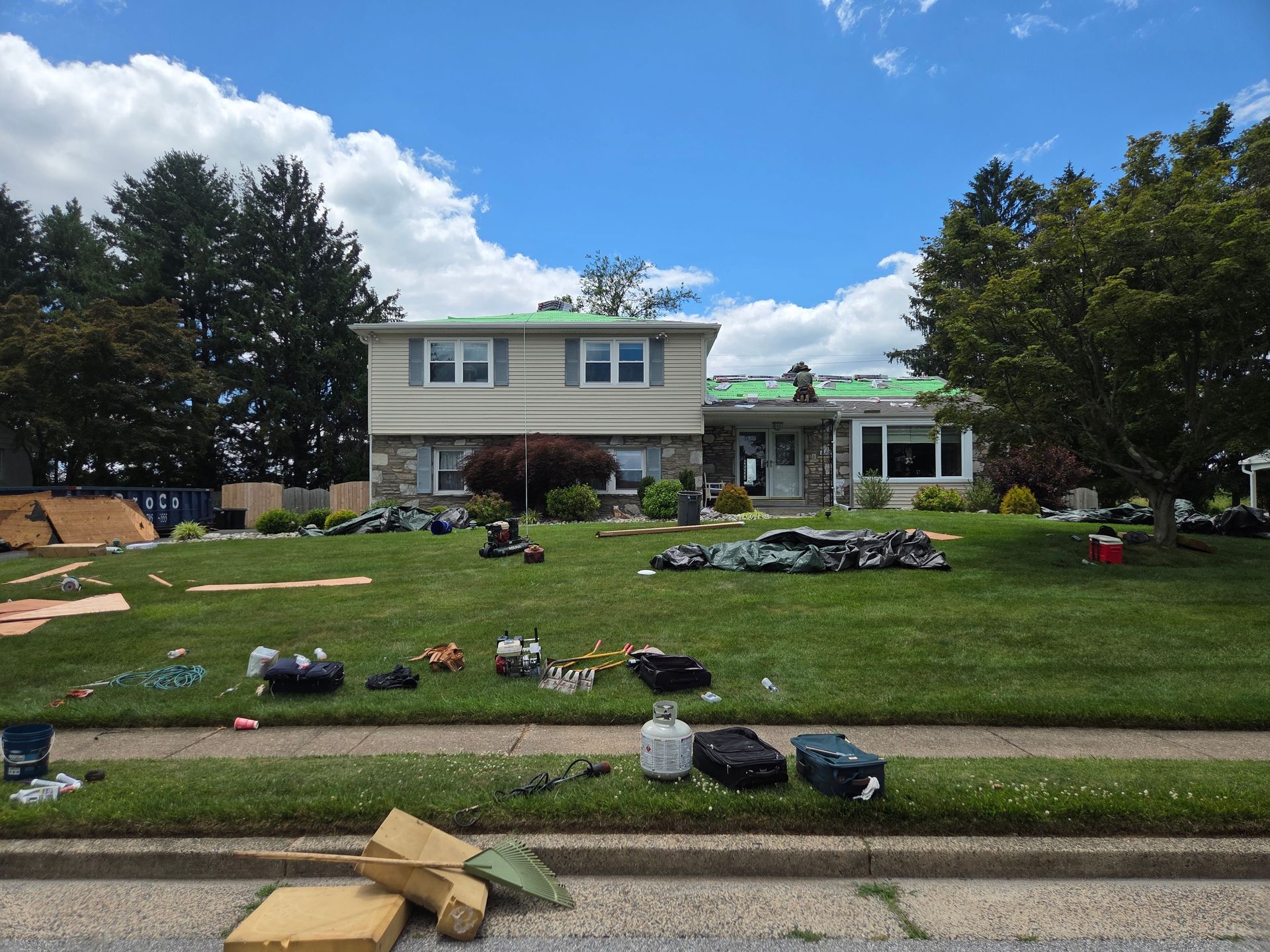 Suburban house with damaged front lawn scattered with debris and trash after a storm.