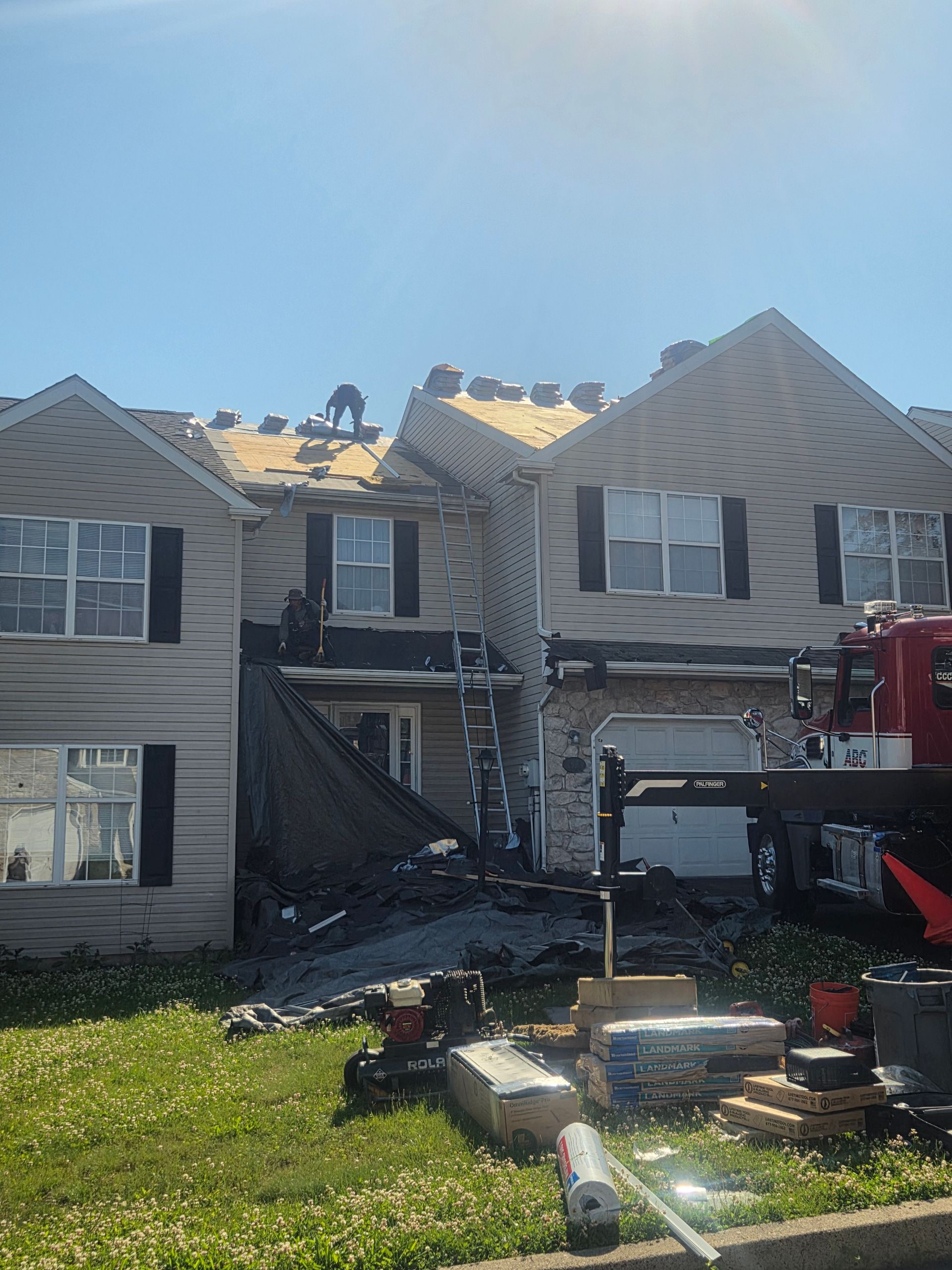 Damaged townhouse row with debris, fire truck, and smoke after a structural fire