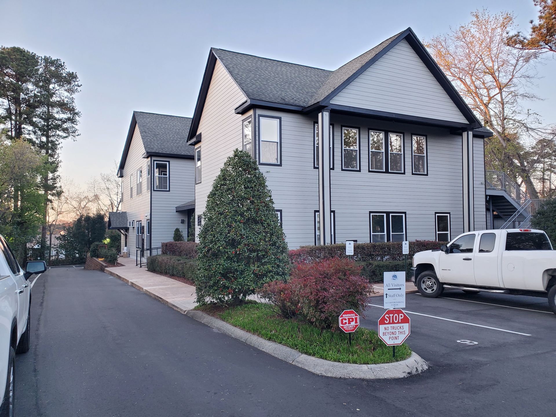 Modern townhouse on a quiet street with parked white truck and small landscaped entrance island