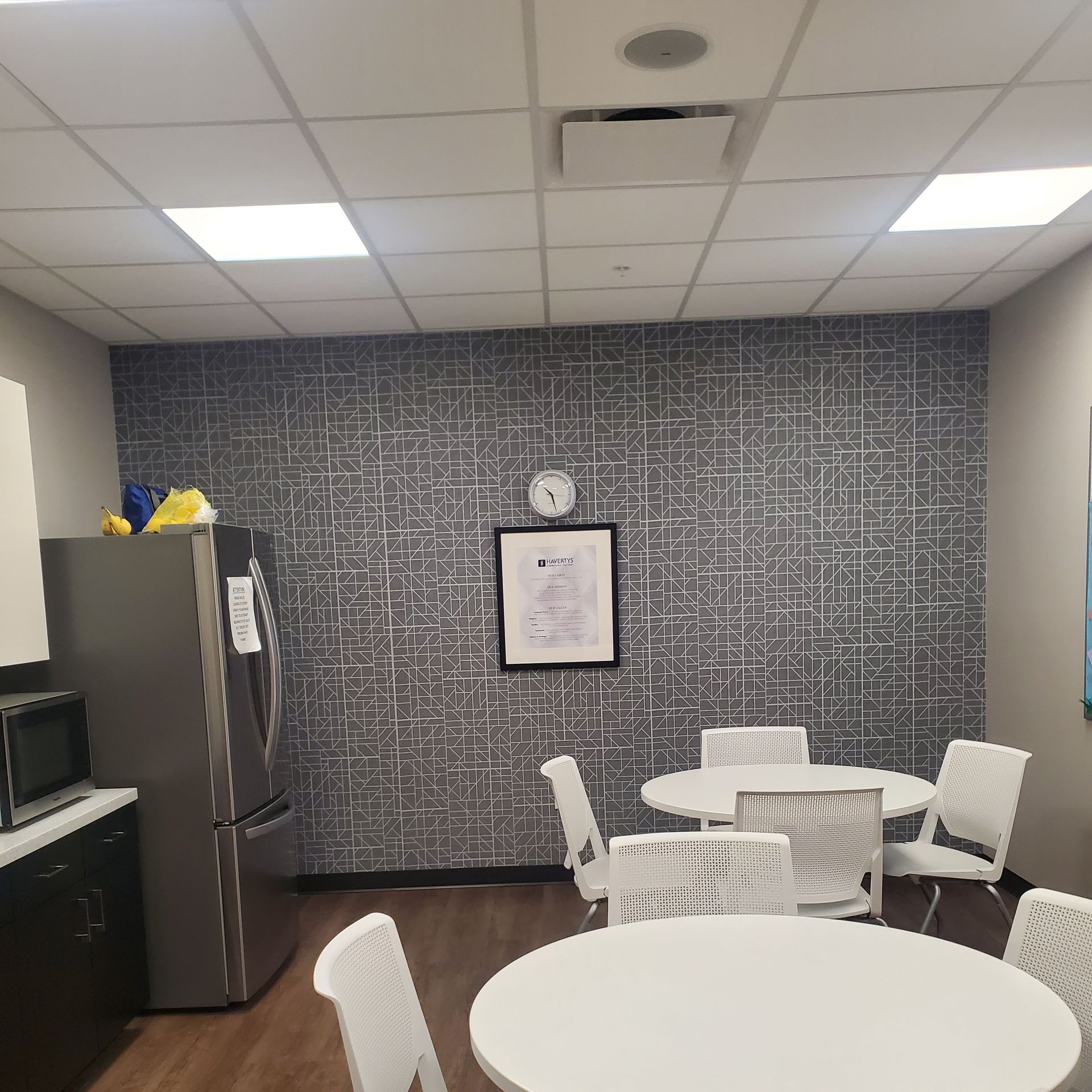 A kitchen with tables and chairs and a clock on the wall