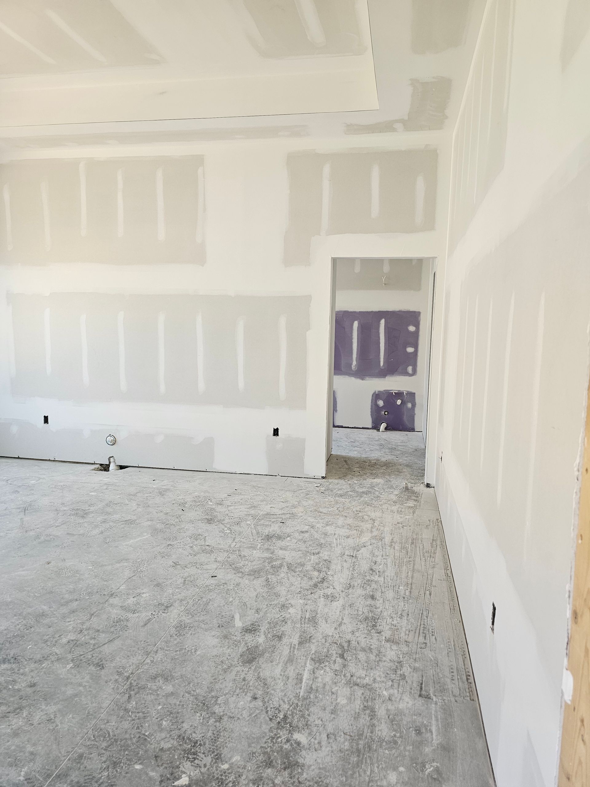 Interior construction with drywall on walls and ceiling, unfinished concrete floor.