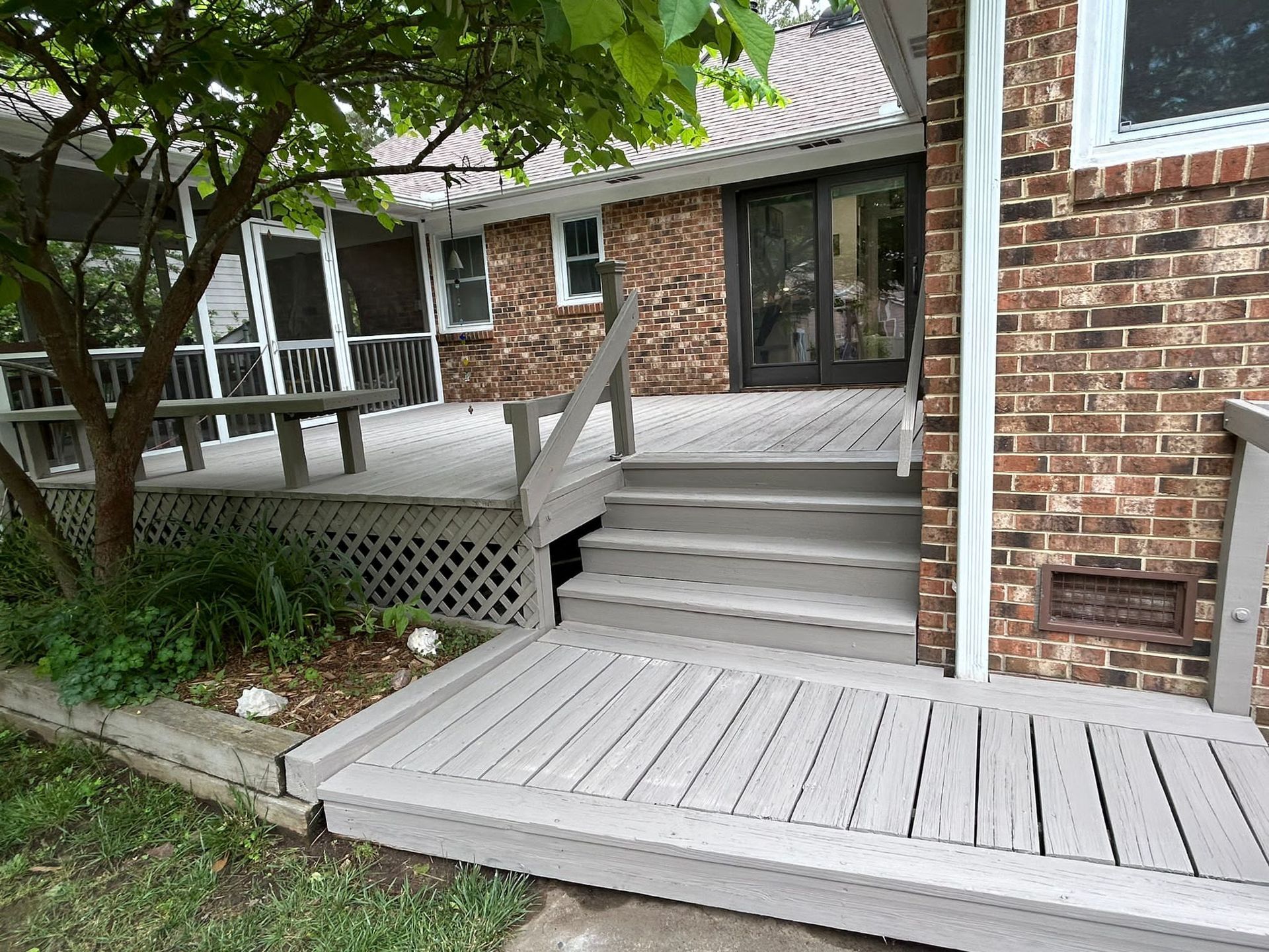 A brick house with a deck and stairs in front of it.