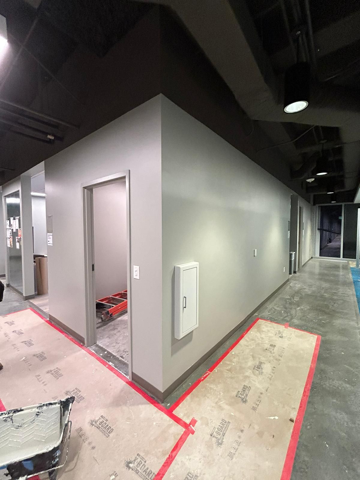 A long hallway with gray walls and a red stripe on the floor.