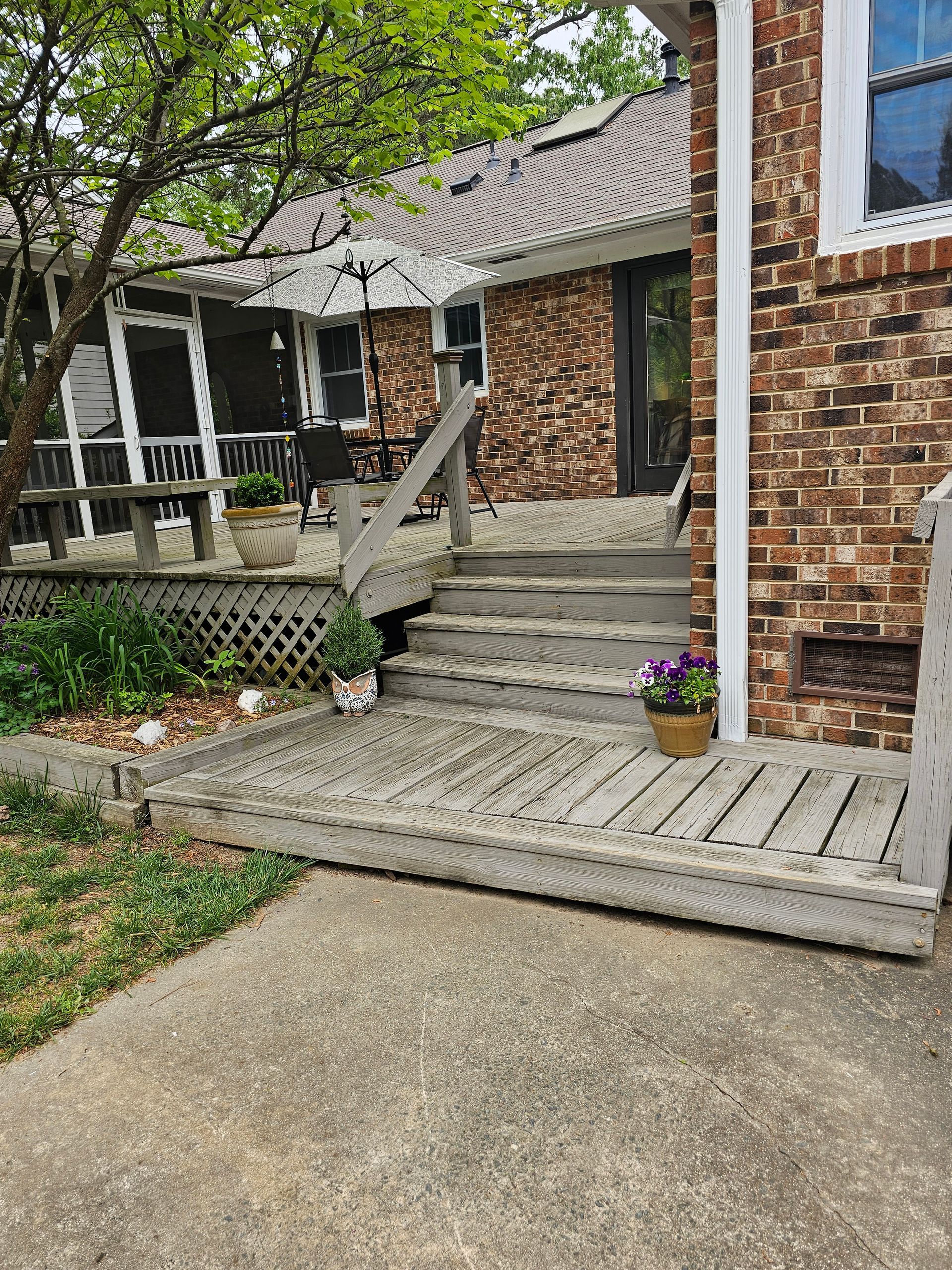 A brick house with a wooden deck and stairs leading up to it.