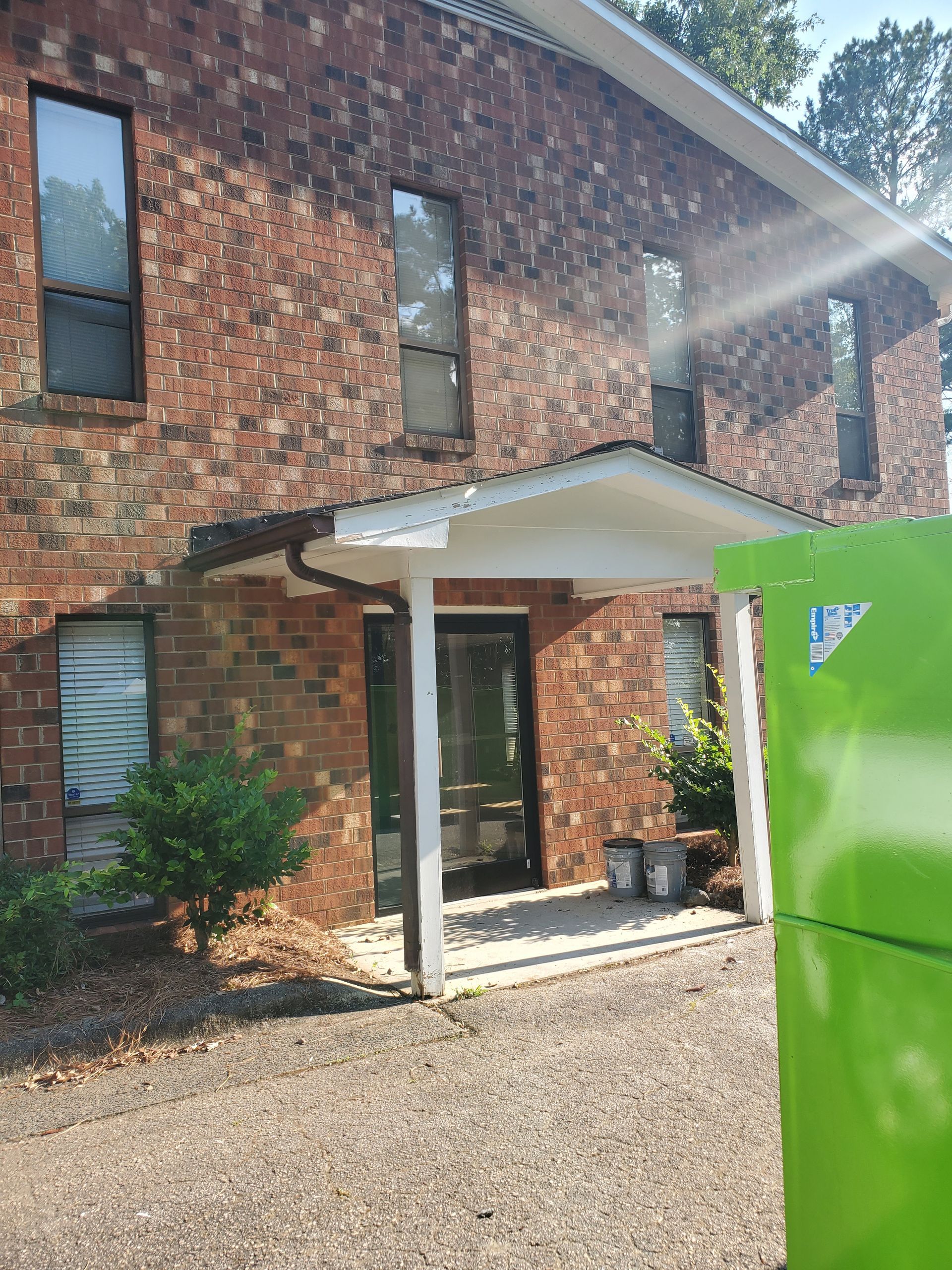 A brick building with a green box in front of it.