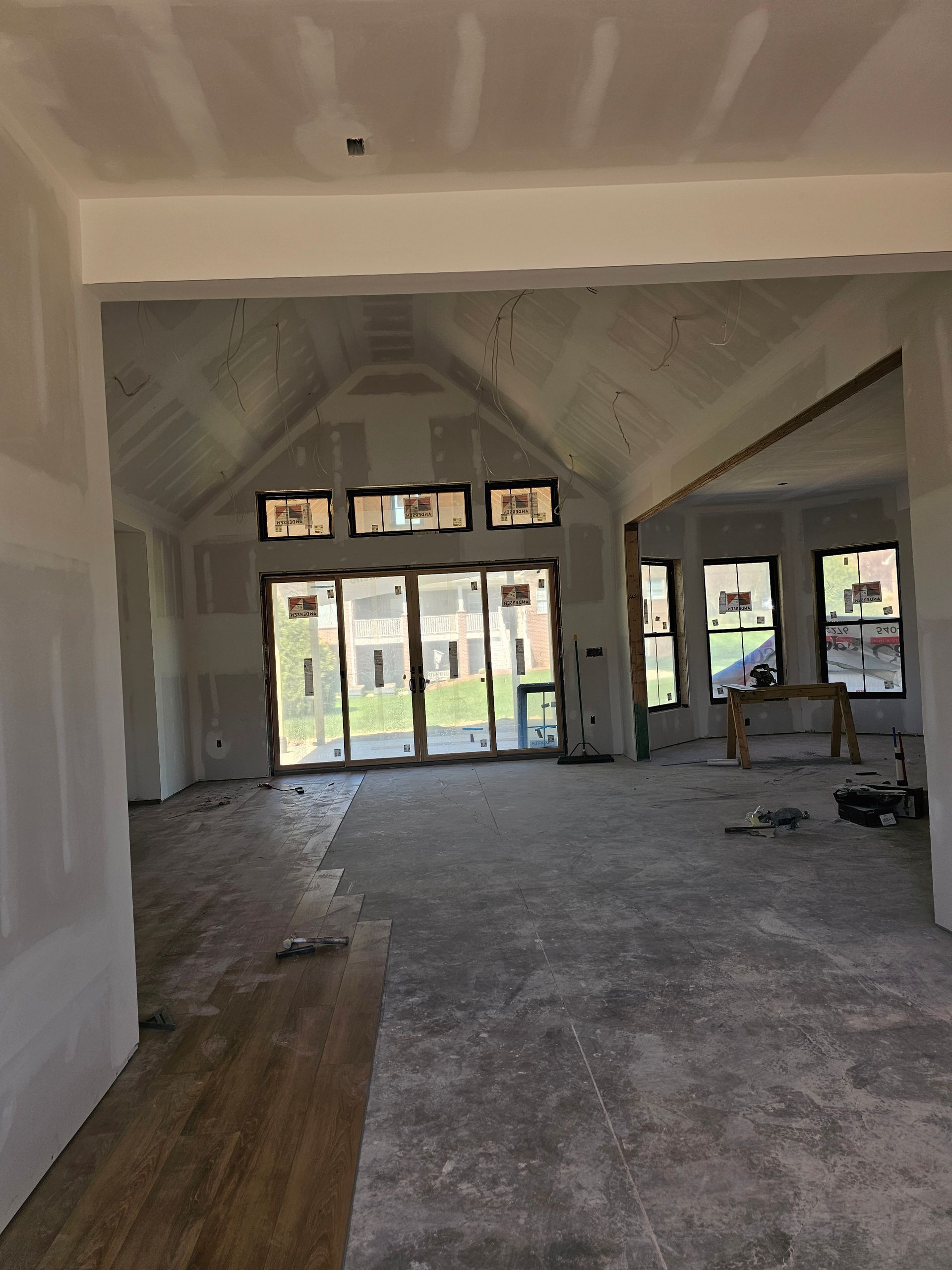 A large empty room with a vaulted ceiling and lots of windows.