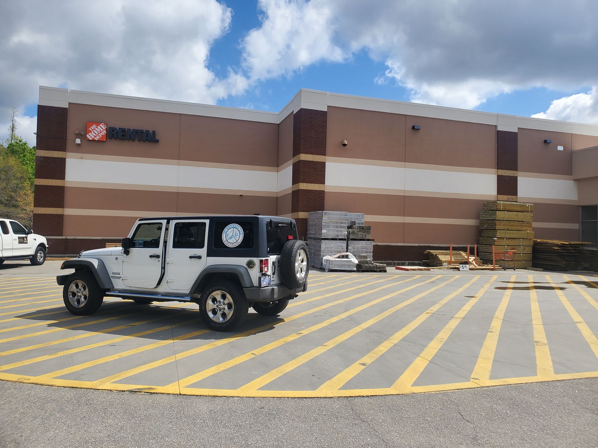 A white jeep is parked in a parking lot in front of a building.