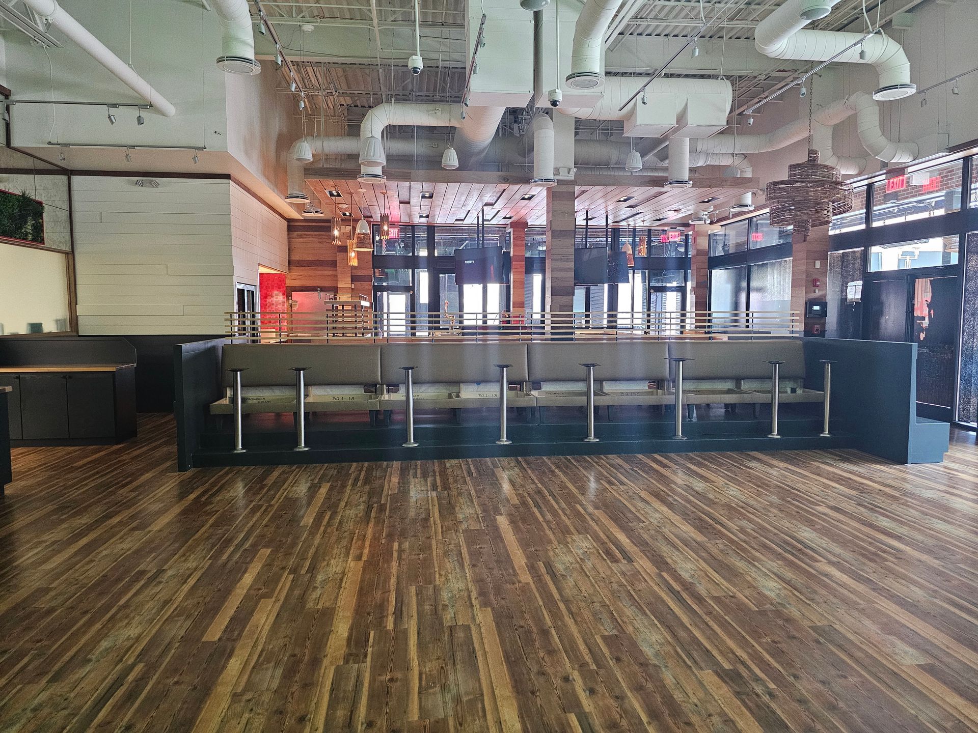 An empty restaurant with a wooden floor and a bar.
