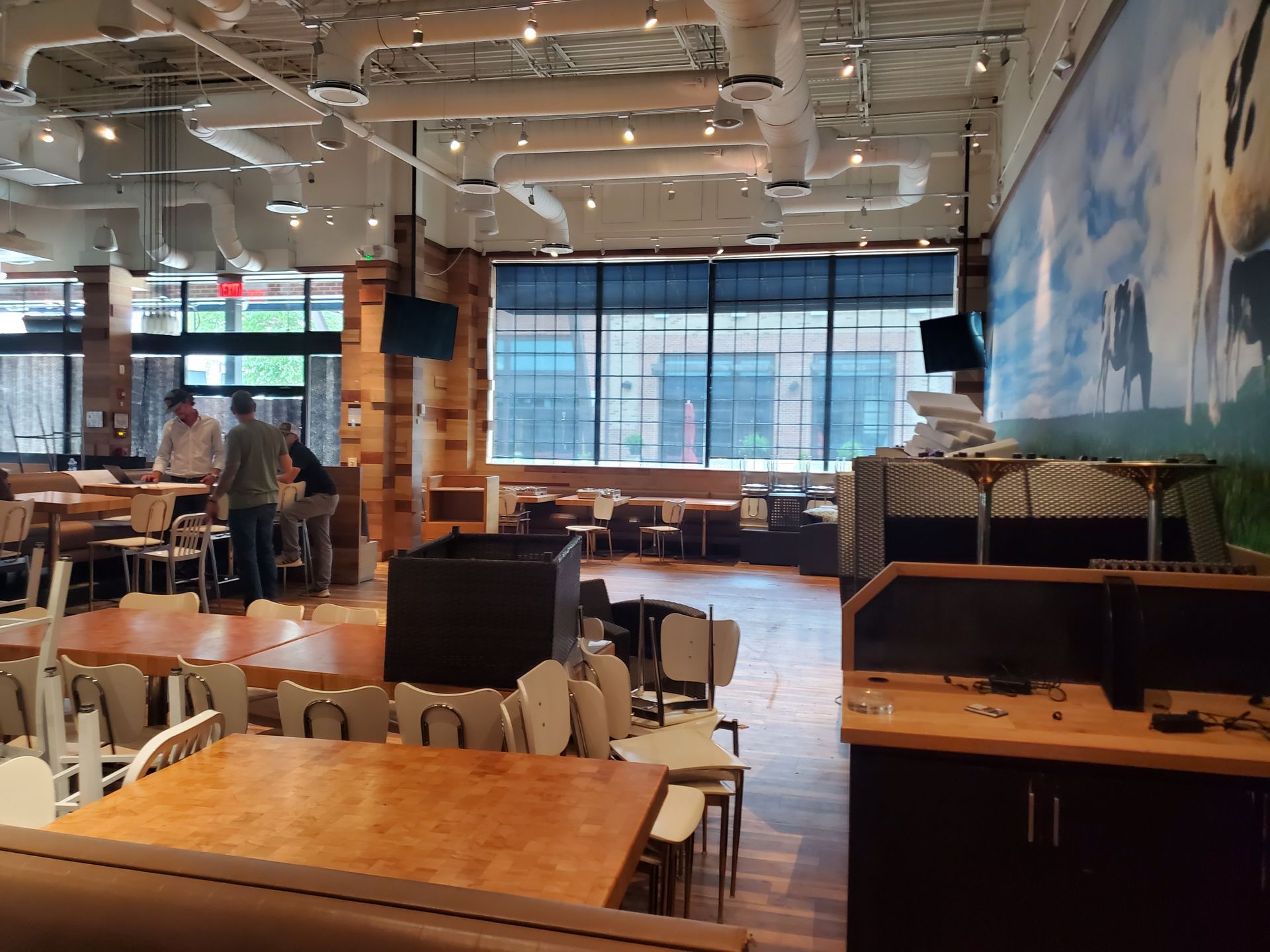 A restaurant with tables and chairs and a large mural on the wall
