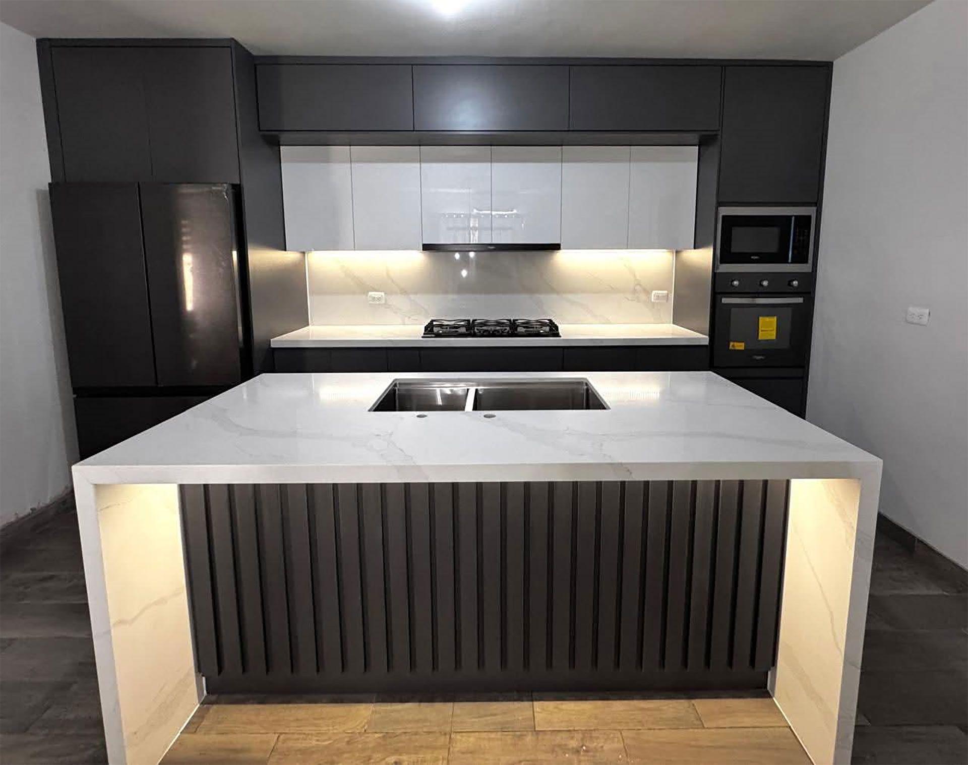 Cocina integral oscura con barra y gabinetes a la medida