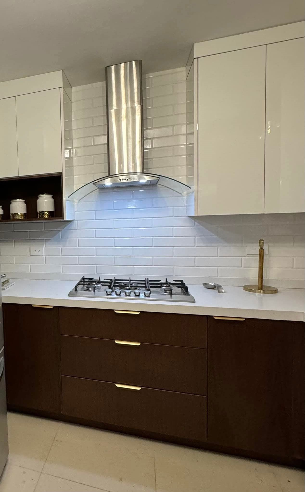Cocina integral blanca con campana de acero y gabinetes de madera