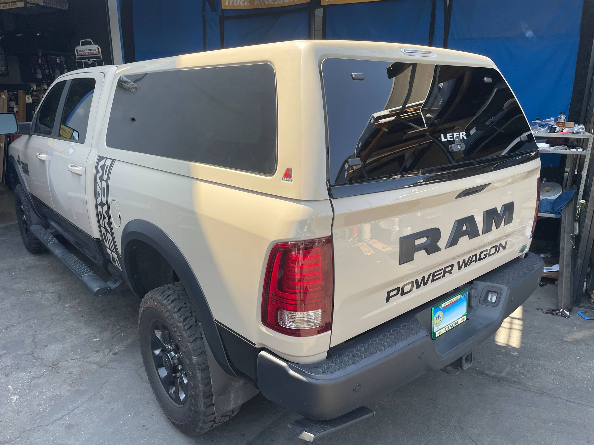 A white ram truck with a canopy is parked in a garage.