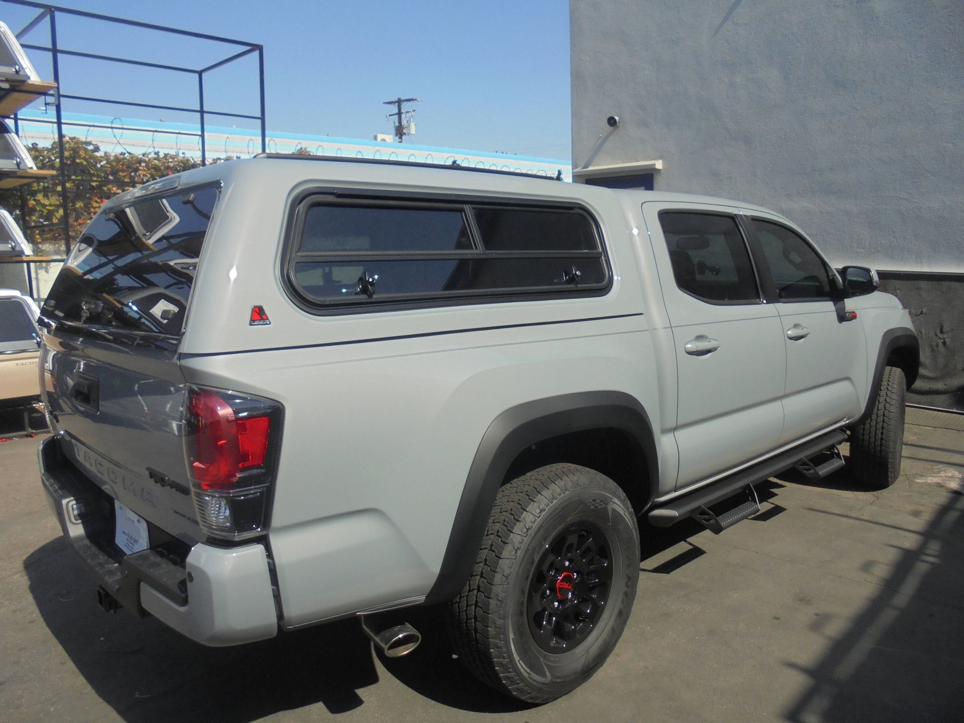 A white truck with a canopy is parked in front of a building.