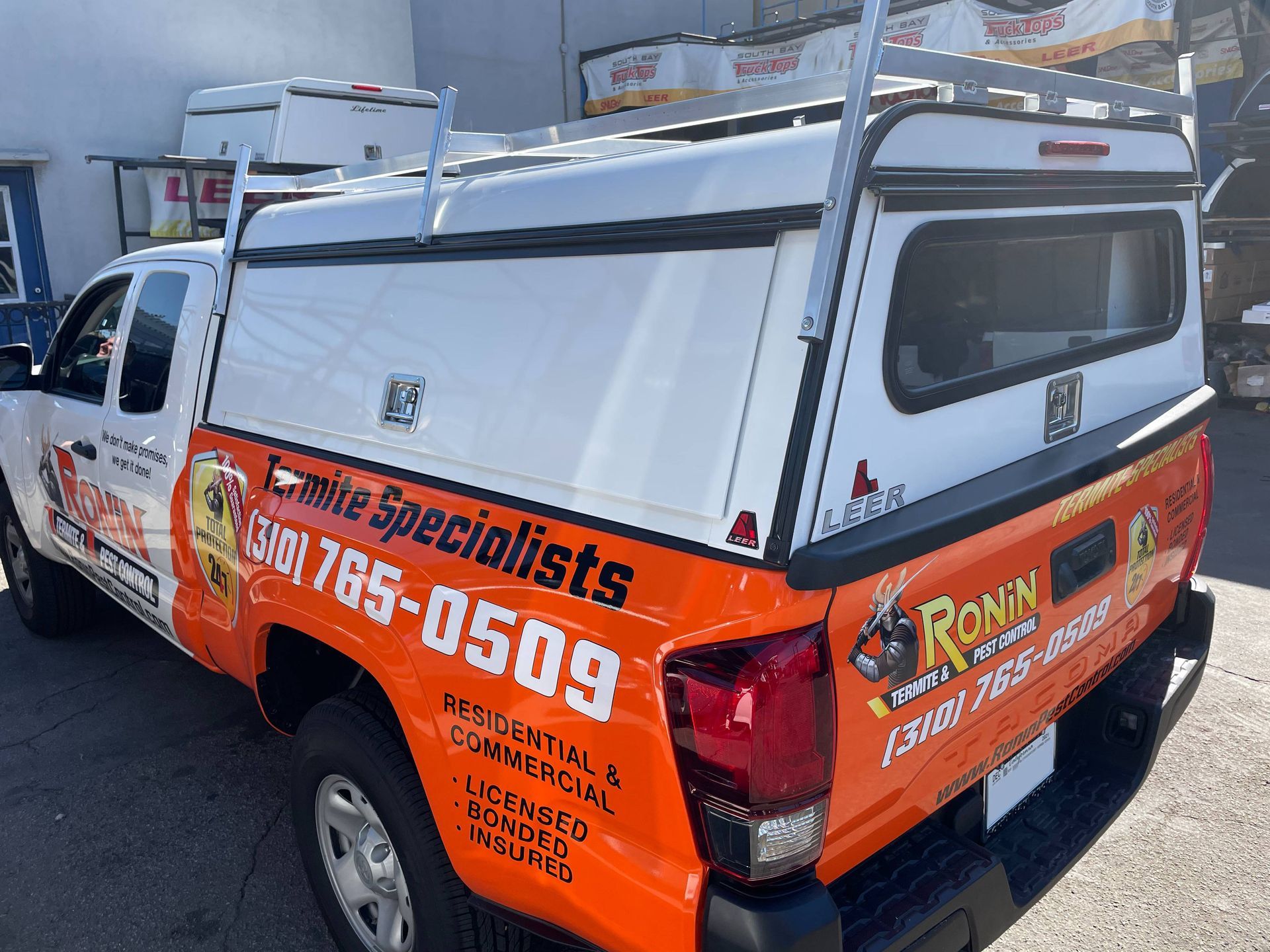 A truck with a canopy on top of it is parked in a parking lot.