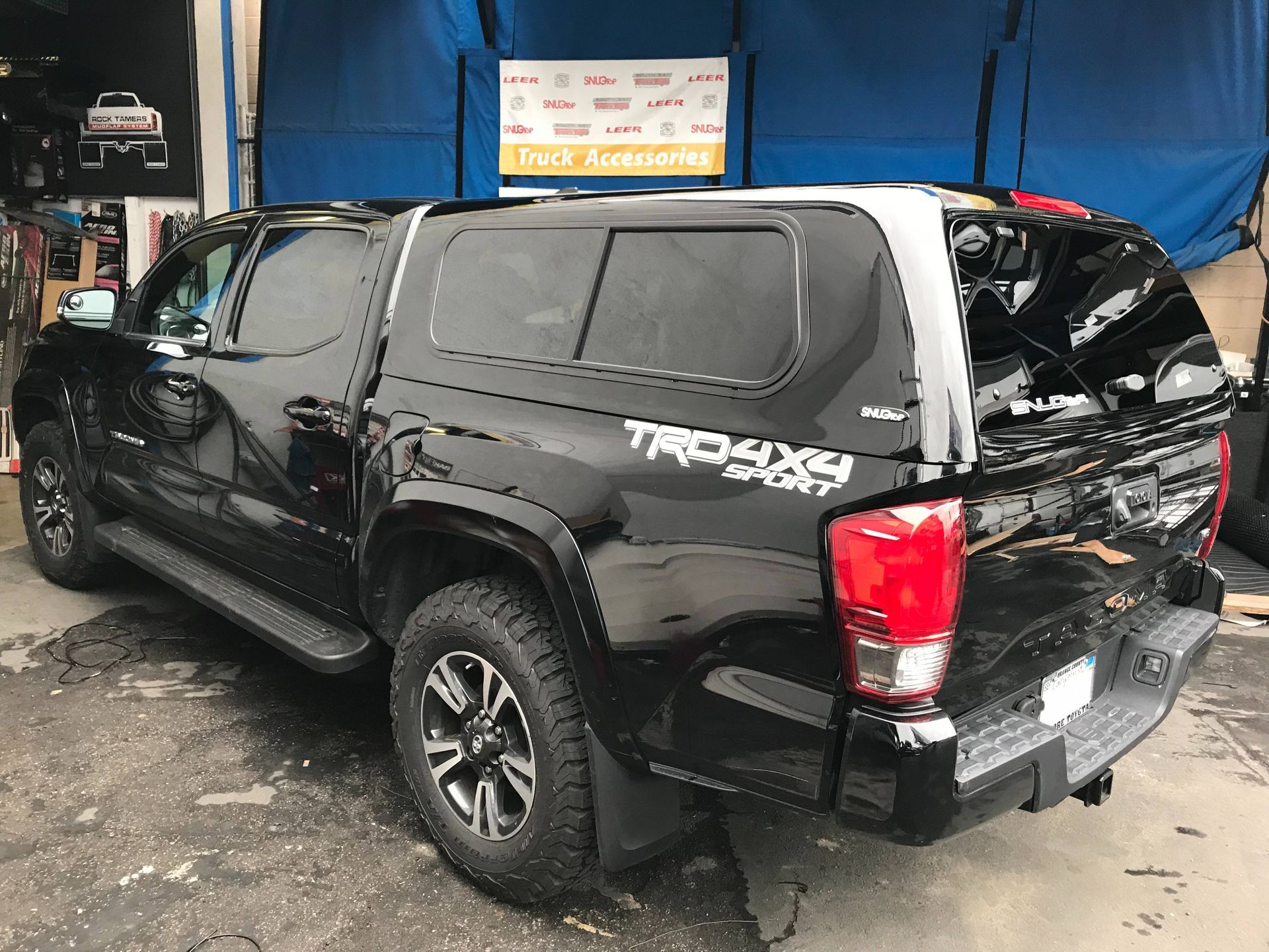 A black truck with a canopy on top of it is parked in a parking lot.