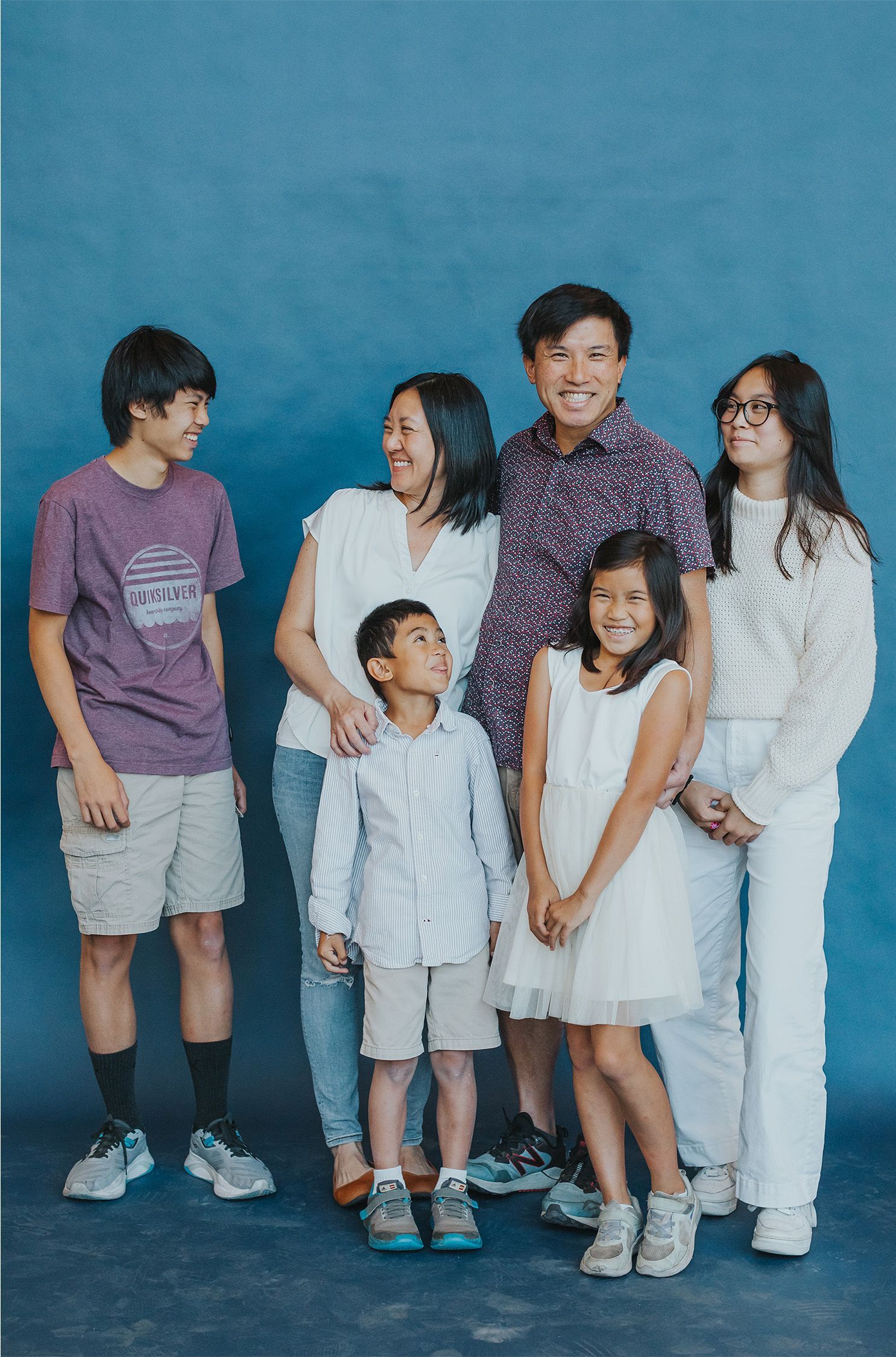 A family is posing for a picture together in front of a blue background.