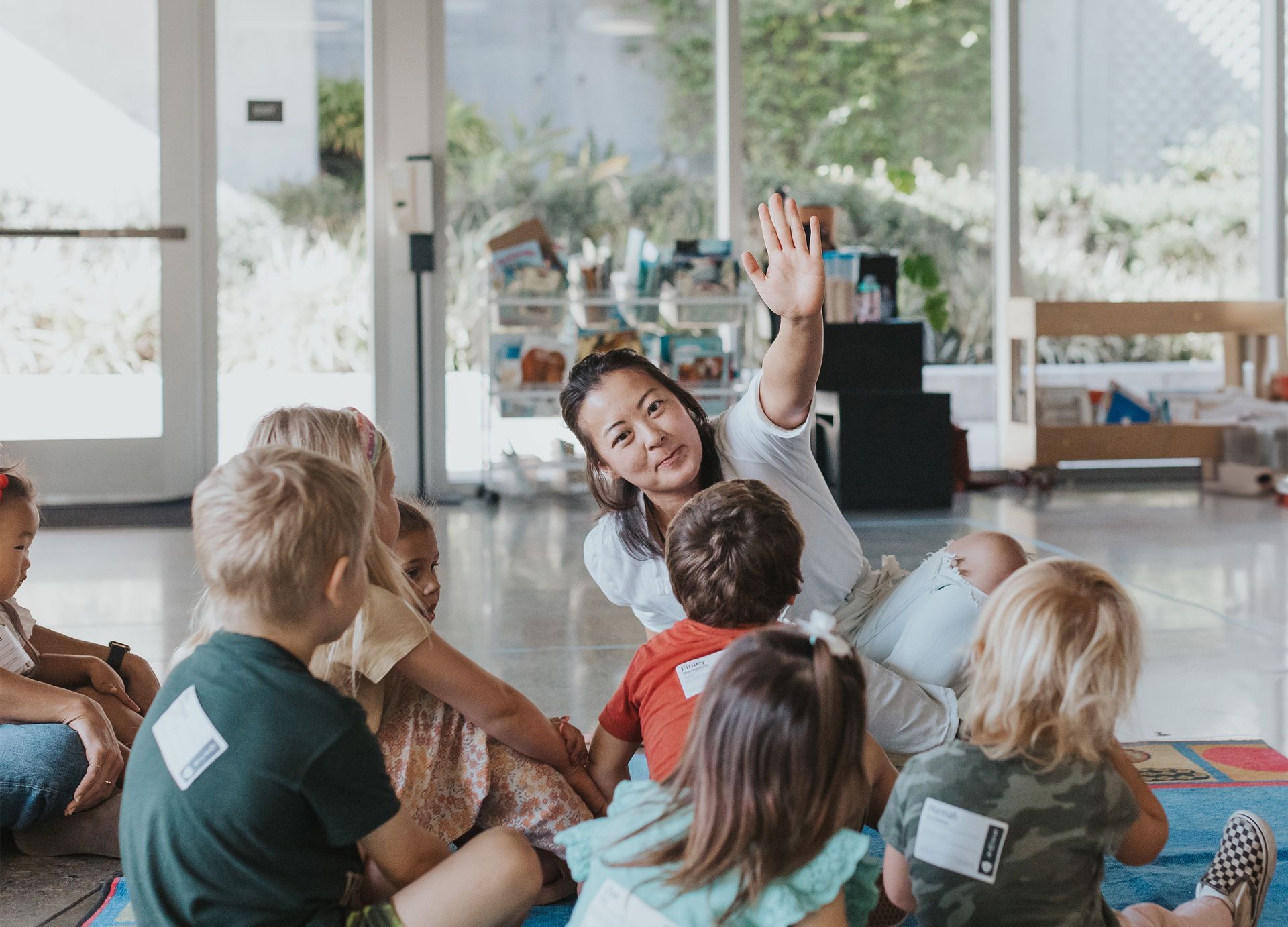 A woman is sitting on the floor with a group of children.