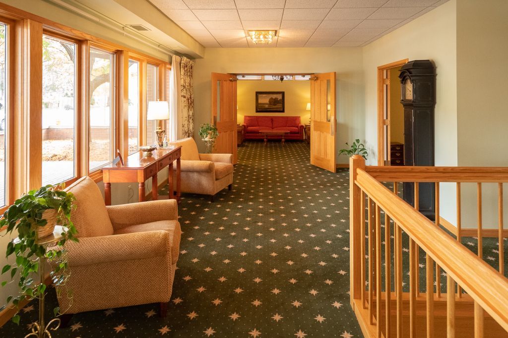a long hallway with a wooden railing and chairs