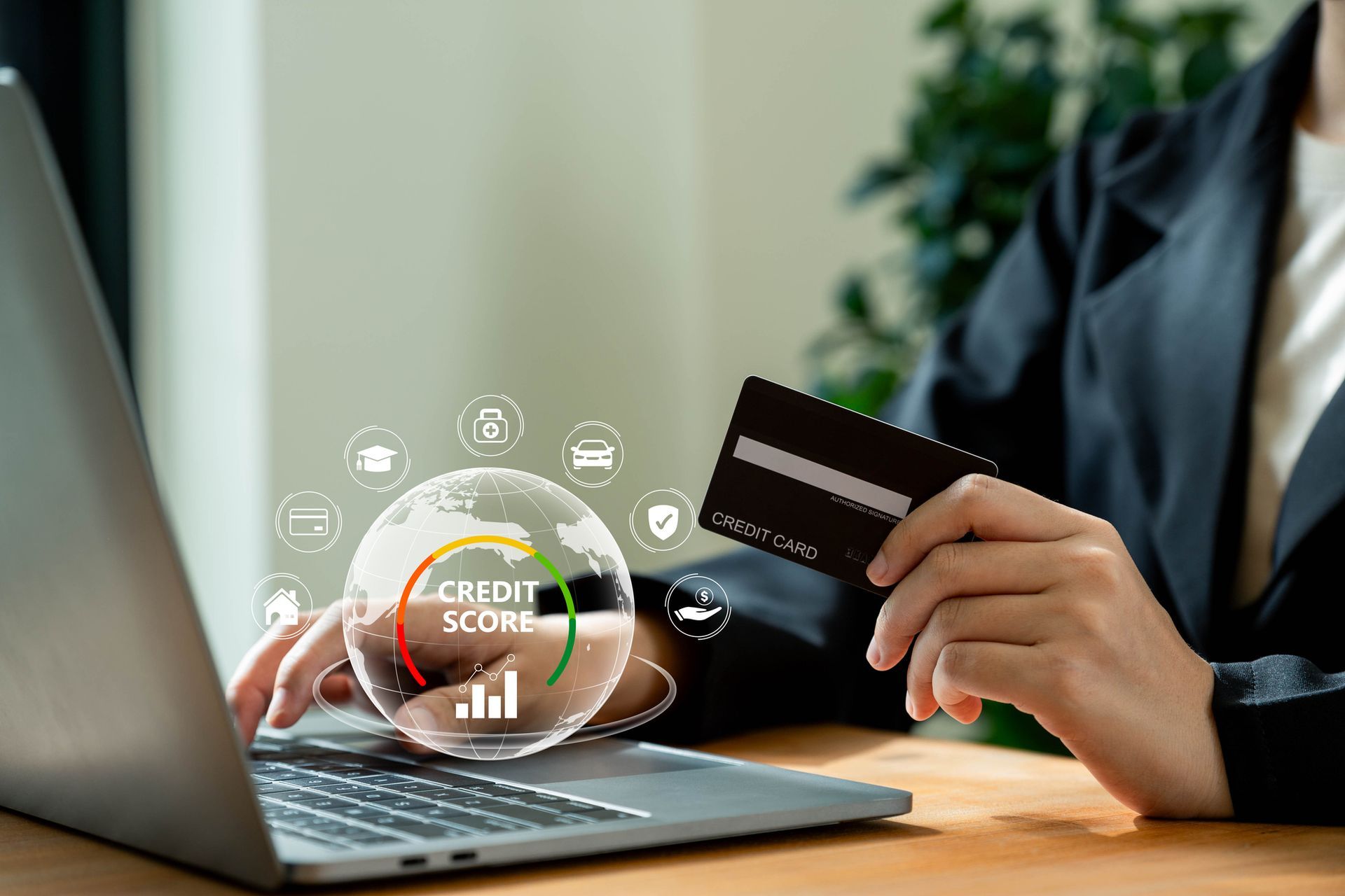 A woman is holding a credit card in front of a laptop computer.