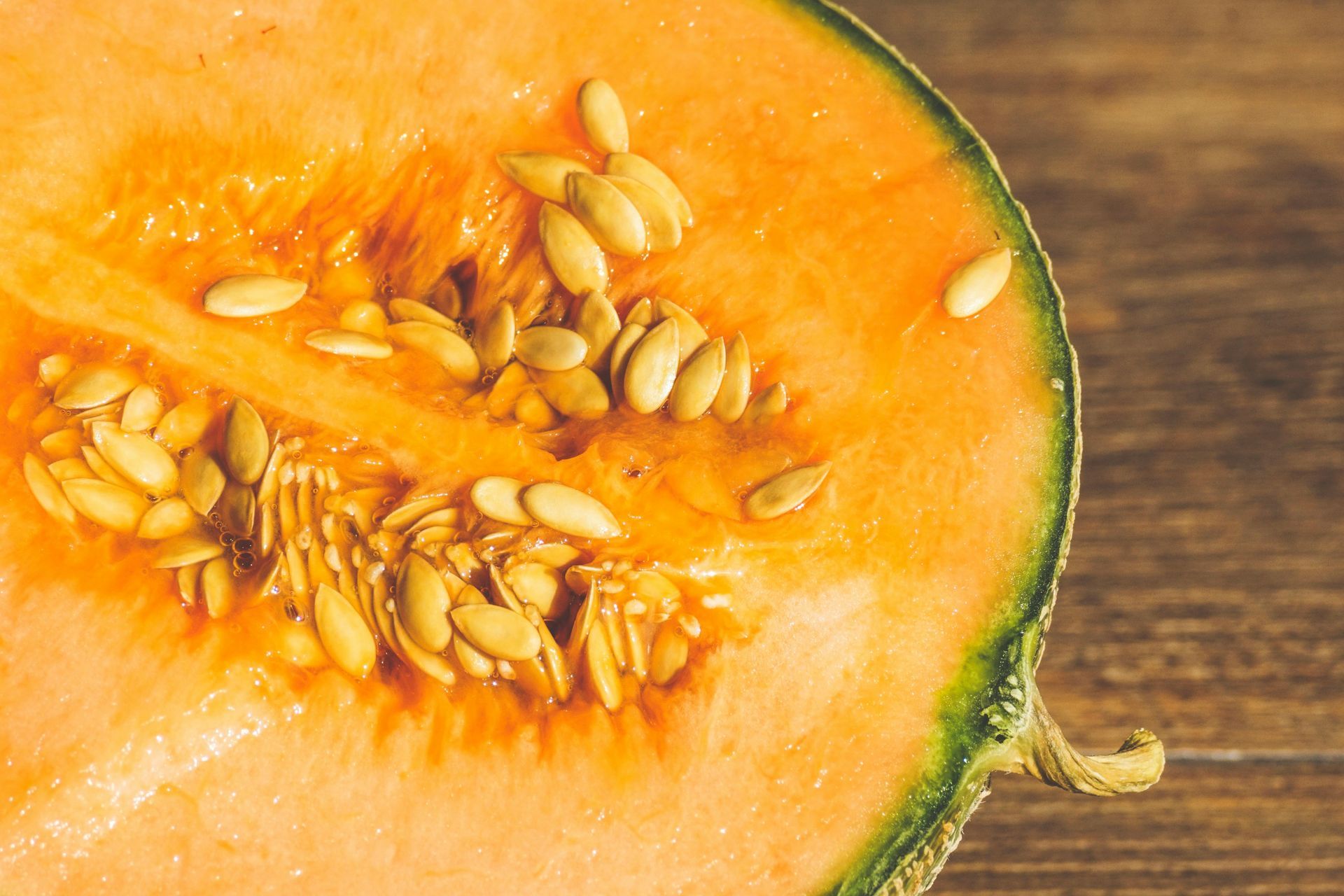 A close up of a cantaloupe cut in half on a wooden table.