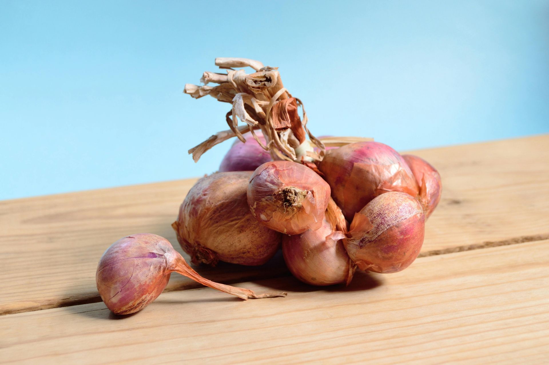 A bunch of onions are sitting on a wooden table.