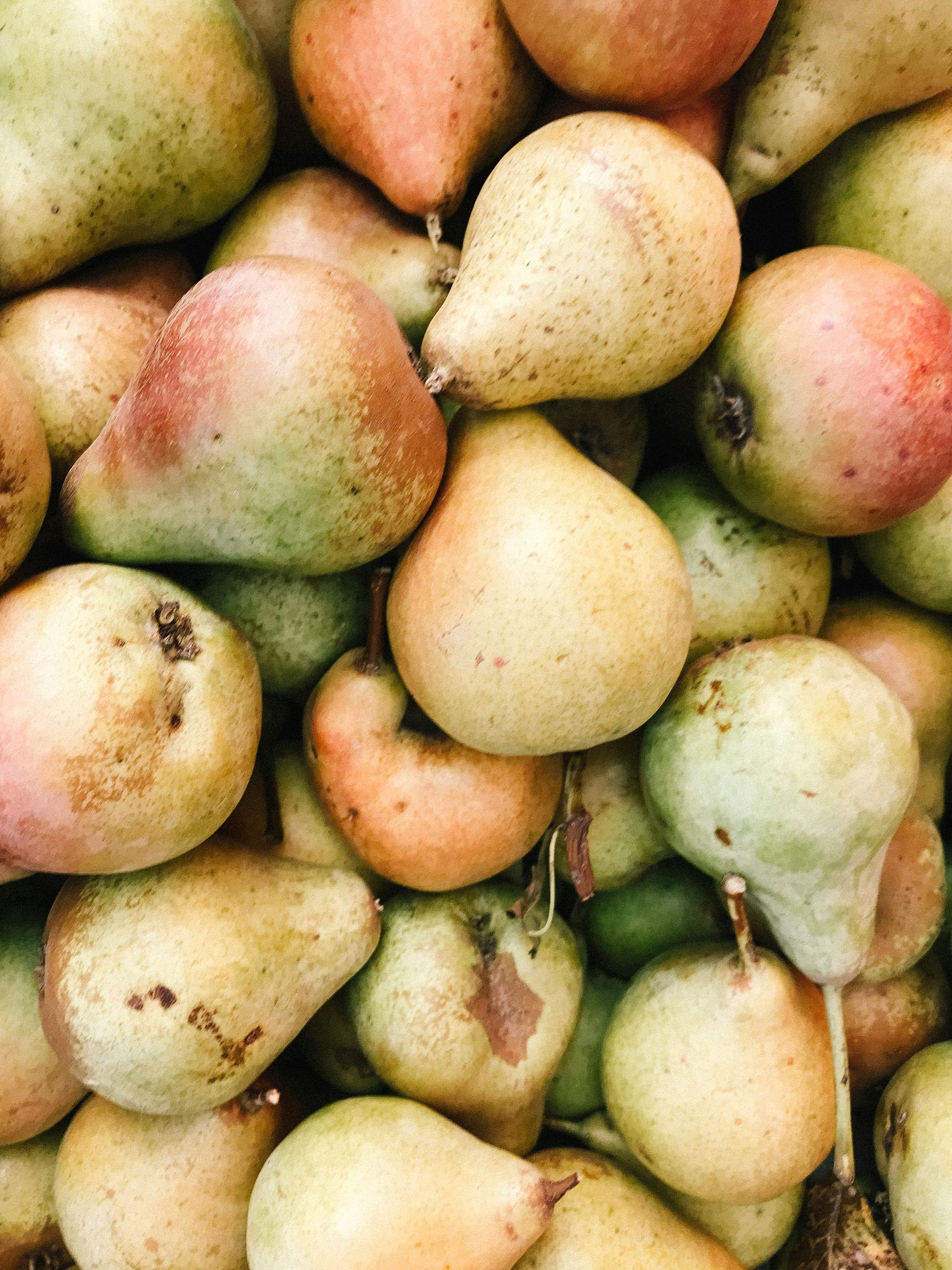 A pile of pears sitting on top of each other on a table.
