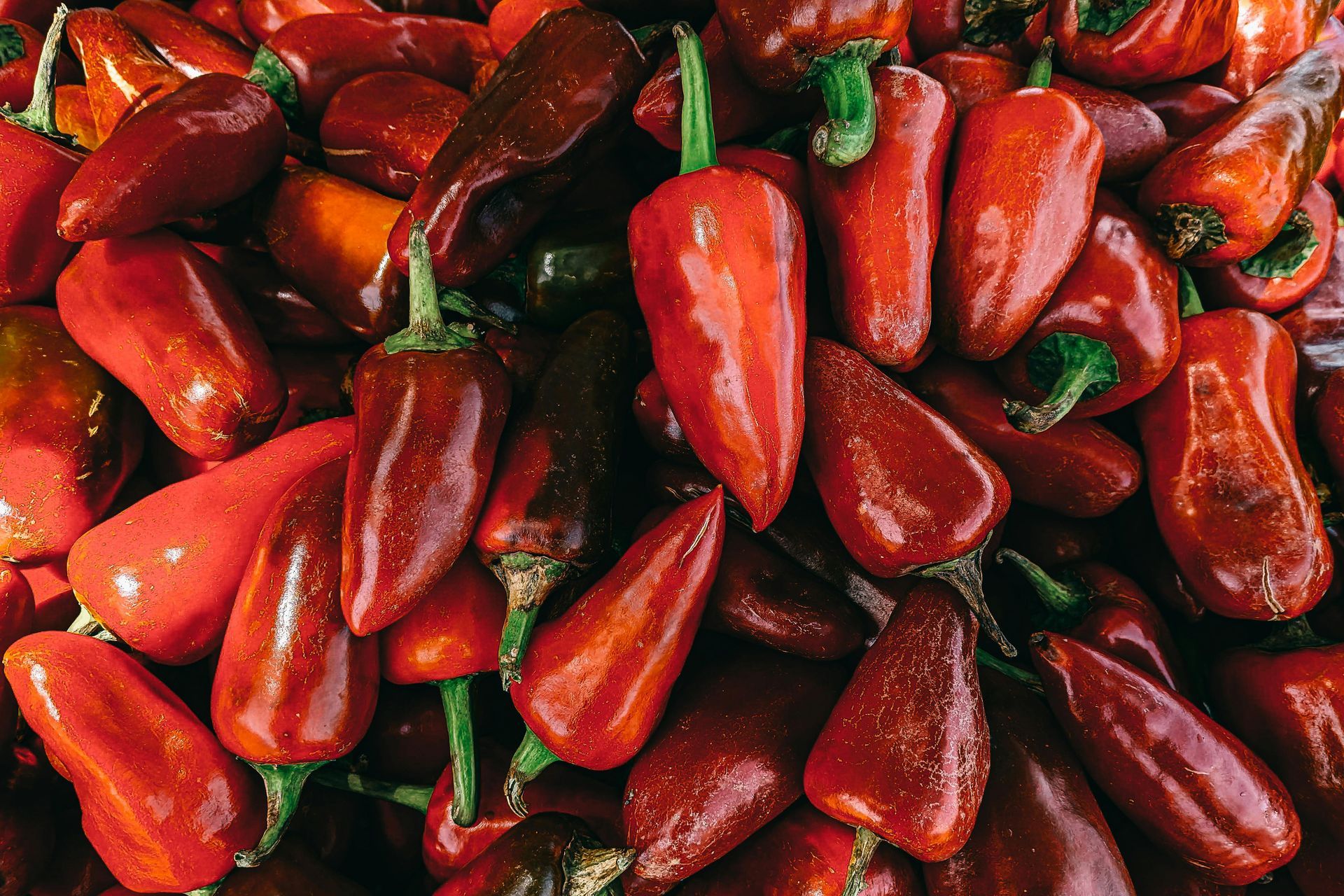 A pile of red peppers with green stems on a table.