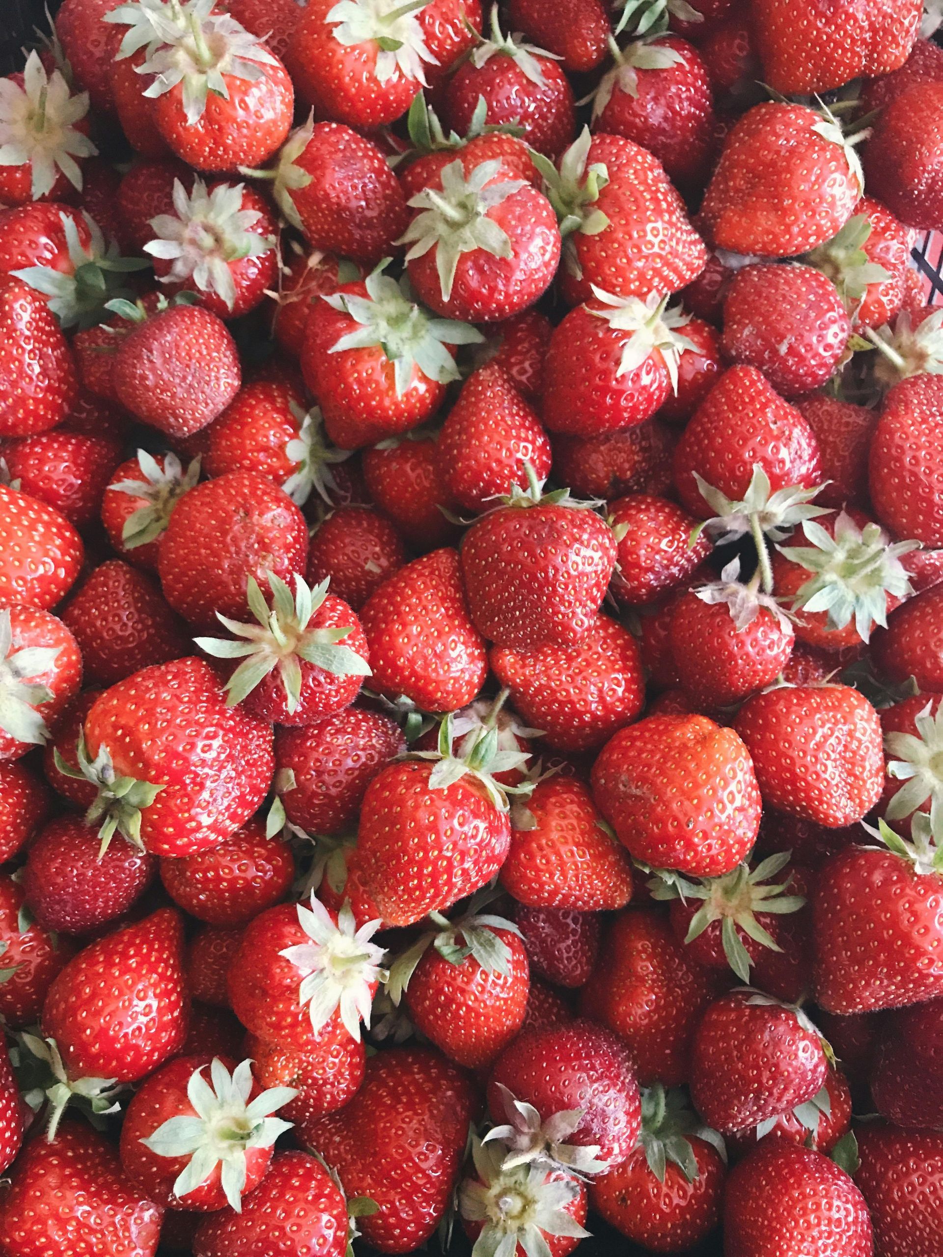 A pile of strawberries with green stems on a table