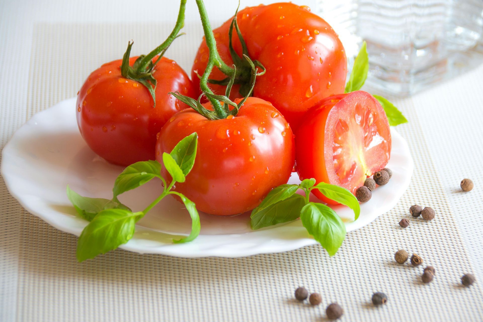 A white plate topped with tomatoes and basil on a table.