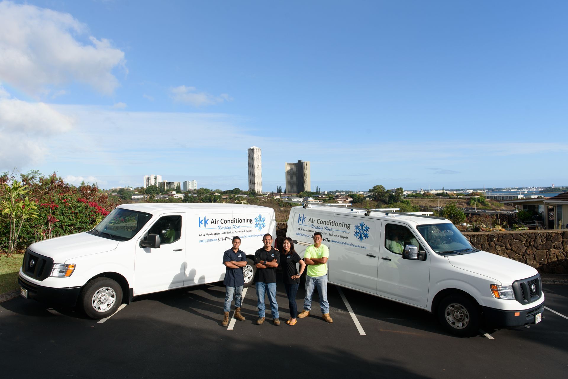 A group of people standing next to two white vans in a parking lot.