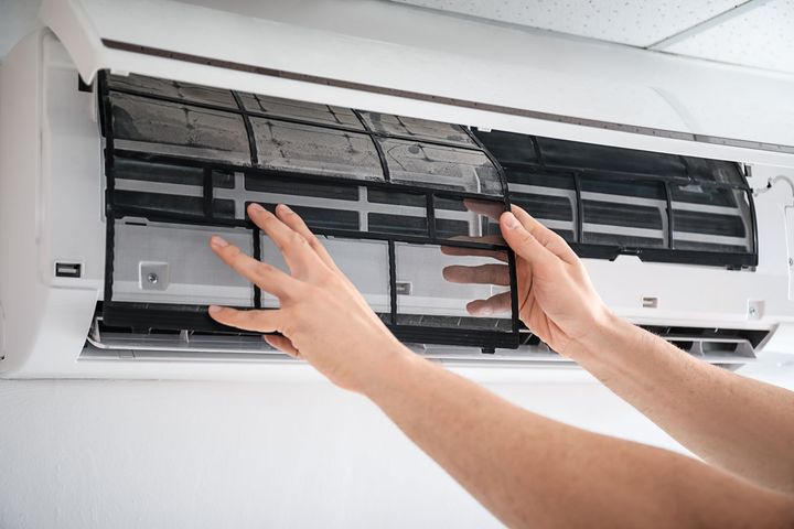 Hands removing a dirty air conditioner filter during maintenance and cleaning process. Hands removing a dirty air conditioner filter during maintenance and cleaning process.