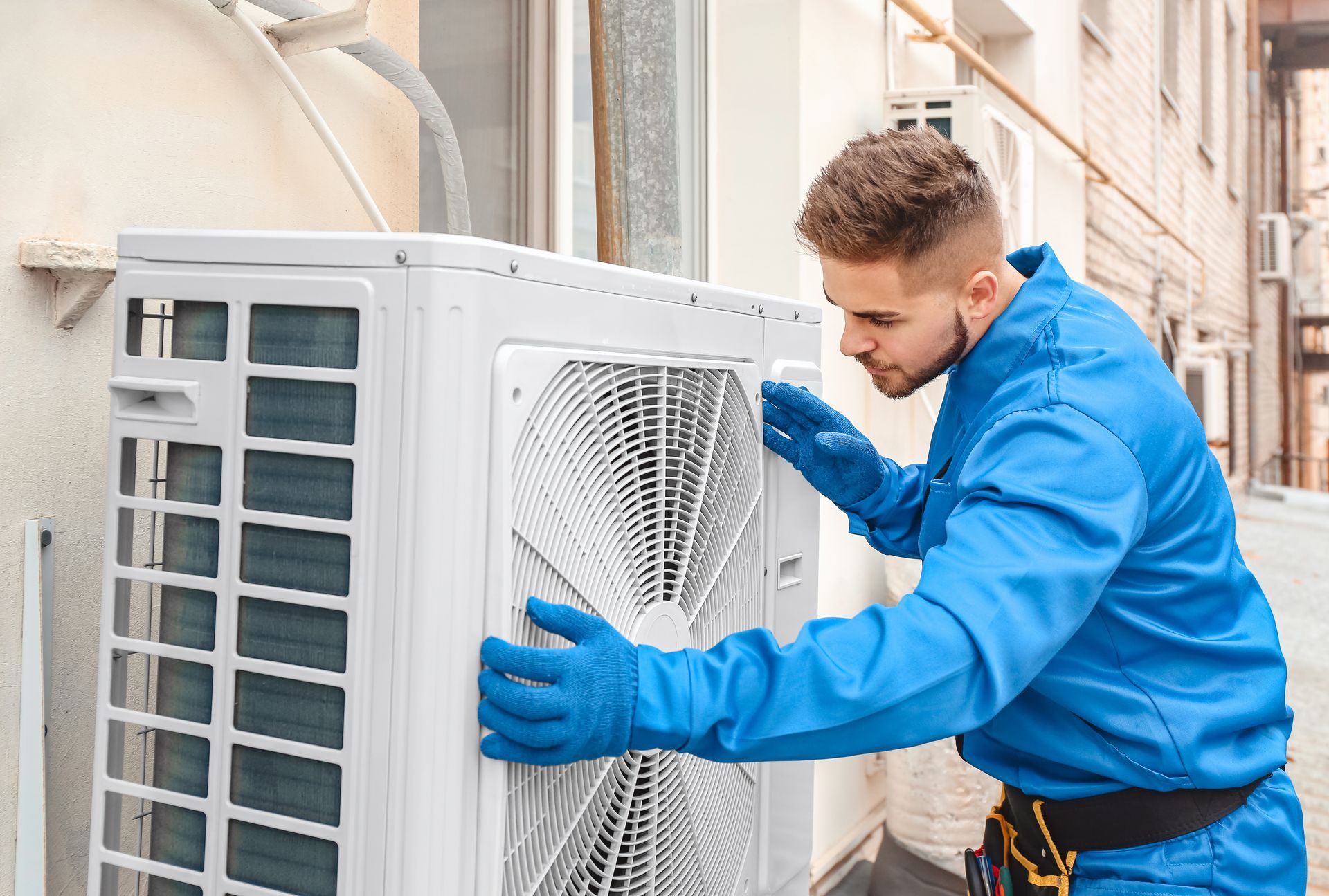 Air conditioning contractor installing and servicing outdoor HVAC unit. Air conditioning contractor installing and servicing outdoor HVAC unit.