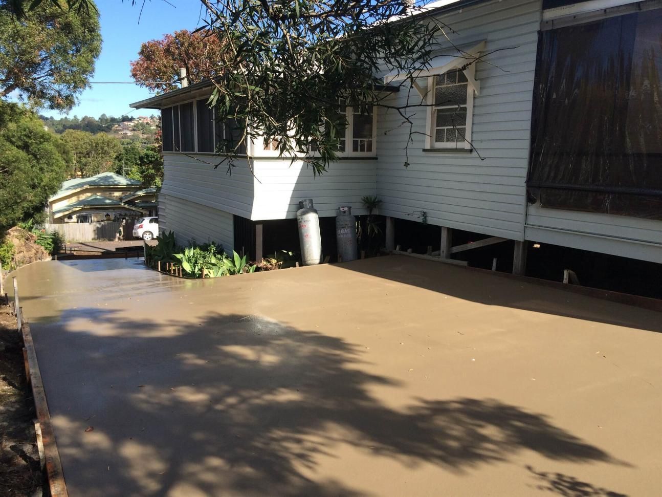 A White House With a Concrete Driveway in Front of It — Wayne Hall Concreting in Lismore, NSW