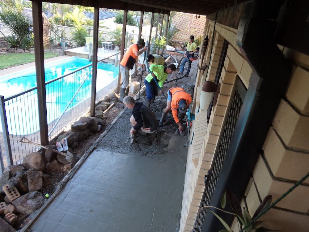 Construction Workers Pouring and Smoothing Concrete Along a House Pathway — Wayne Hall Concreting in South Lismore, NSW