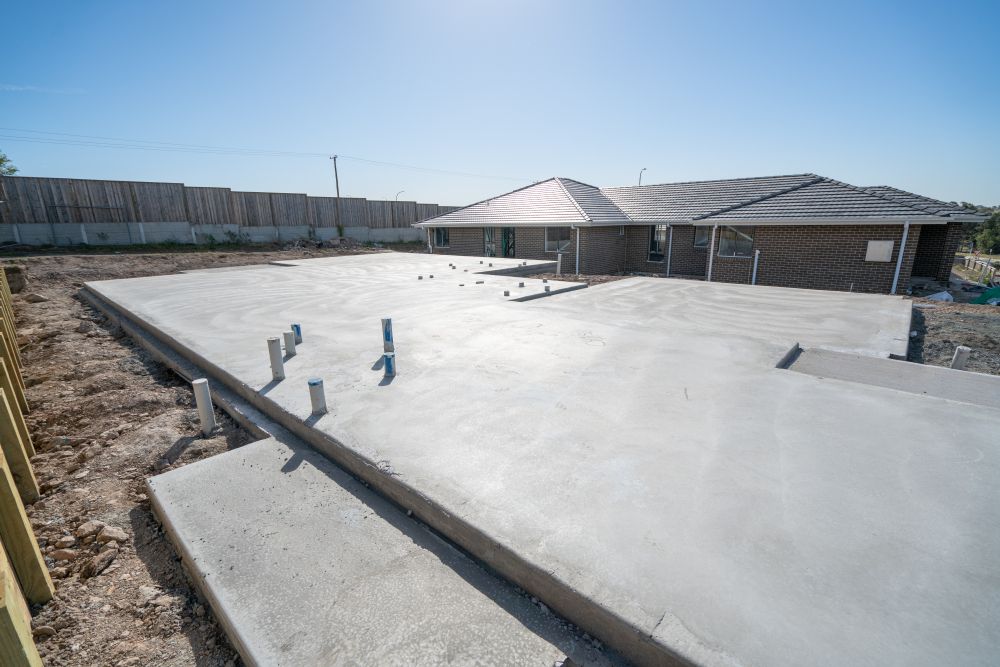 A large concrete slab is sitting in the backyard with house in background — Wayne Hall Concreting in Casino, NSW