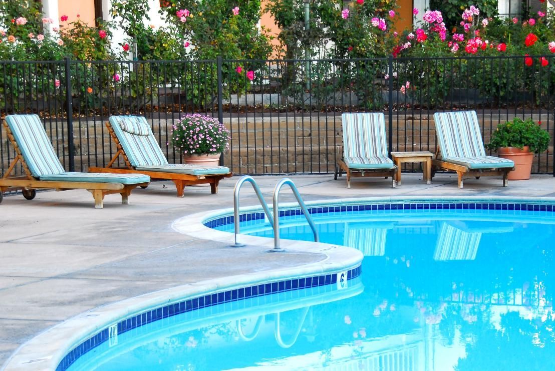 A Large Swimming Pool Surrounded by Chairs and a Fence — Wayne Hall Concreting in South Lismore, NSW