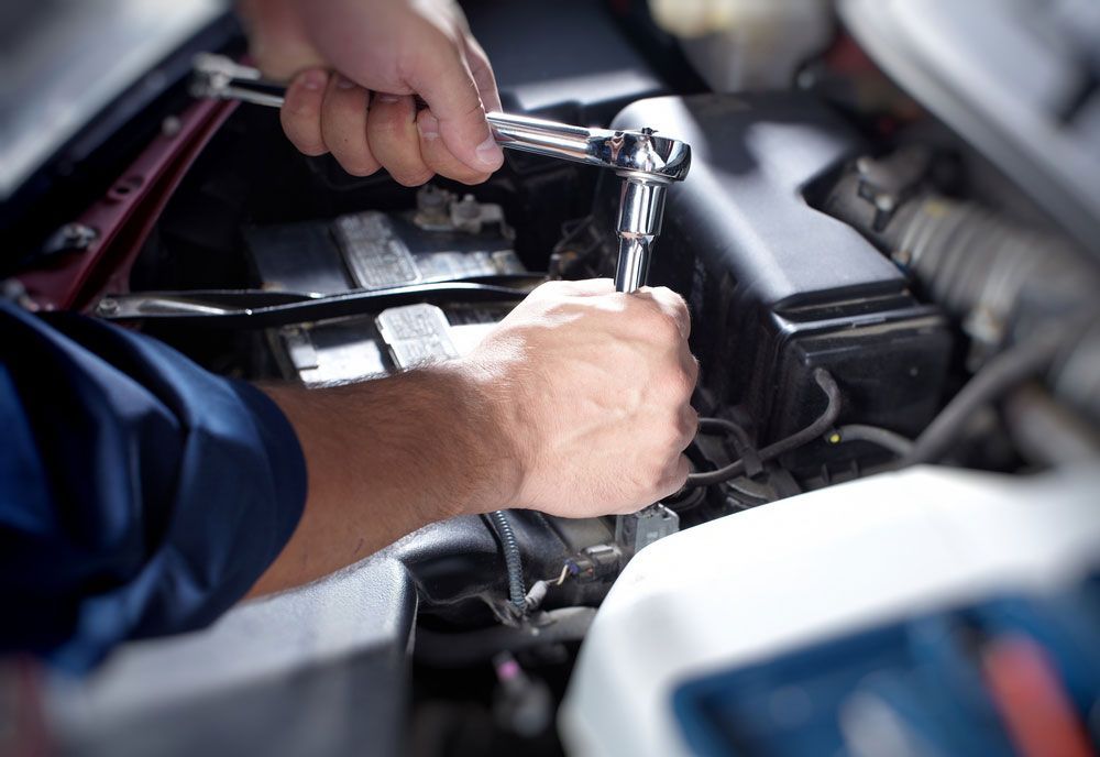 A Man Is Working On The Engine Of A Car With A Wrench — Coffs Harbour Automotive In Coffs Harbour, NSW