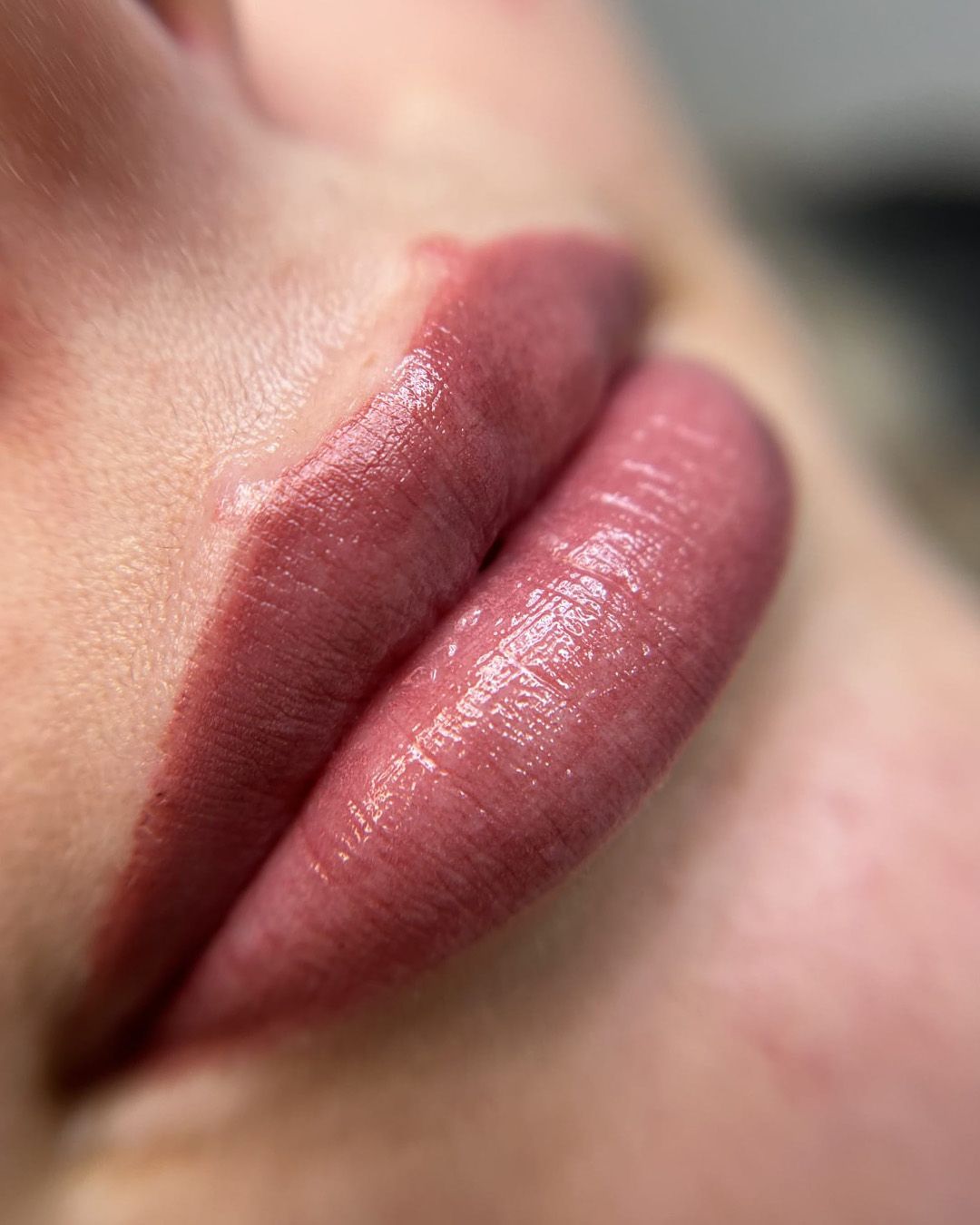 Close-up van volle, glanzende lippen in een gedempte, roze-bruine tint.